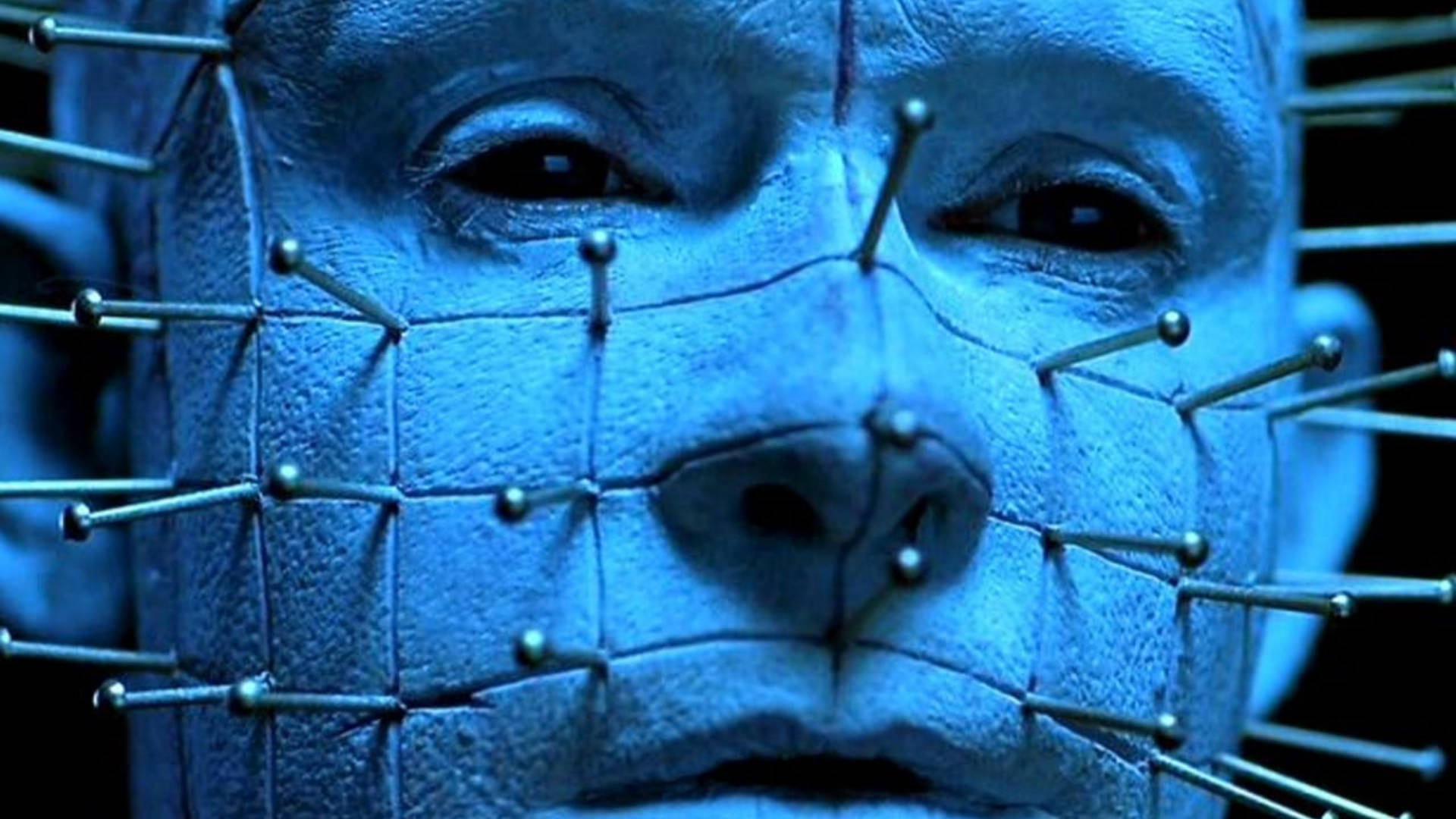 horror villains 桌布 壁紙 — 戲劇性燈光下，金屬針以網格圖案刺穿淡藍色臉部的特寫。