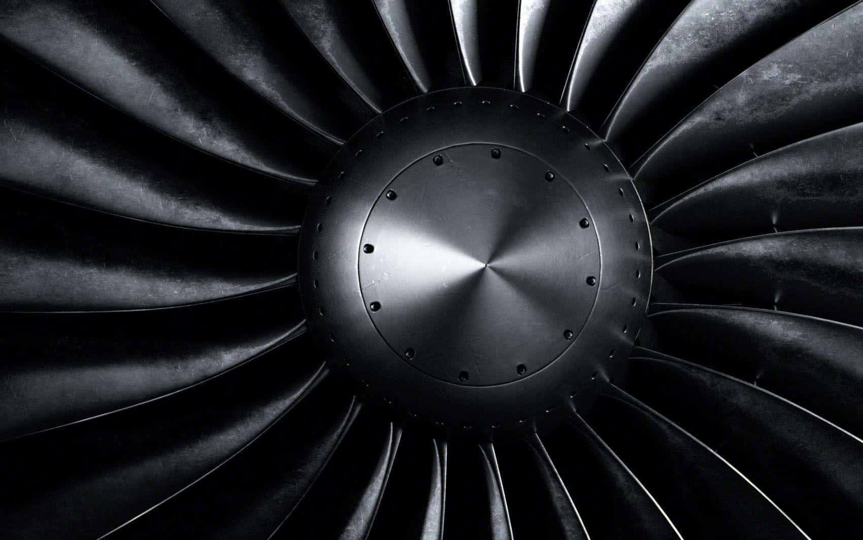 Jet Engine 桌布 壁紙 — 戲劇性燈光下噴射引擎渦輪機的近距離特寫，帶有徑向葉片和中央輪轂。