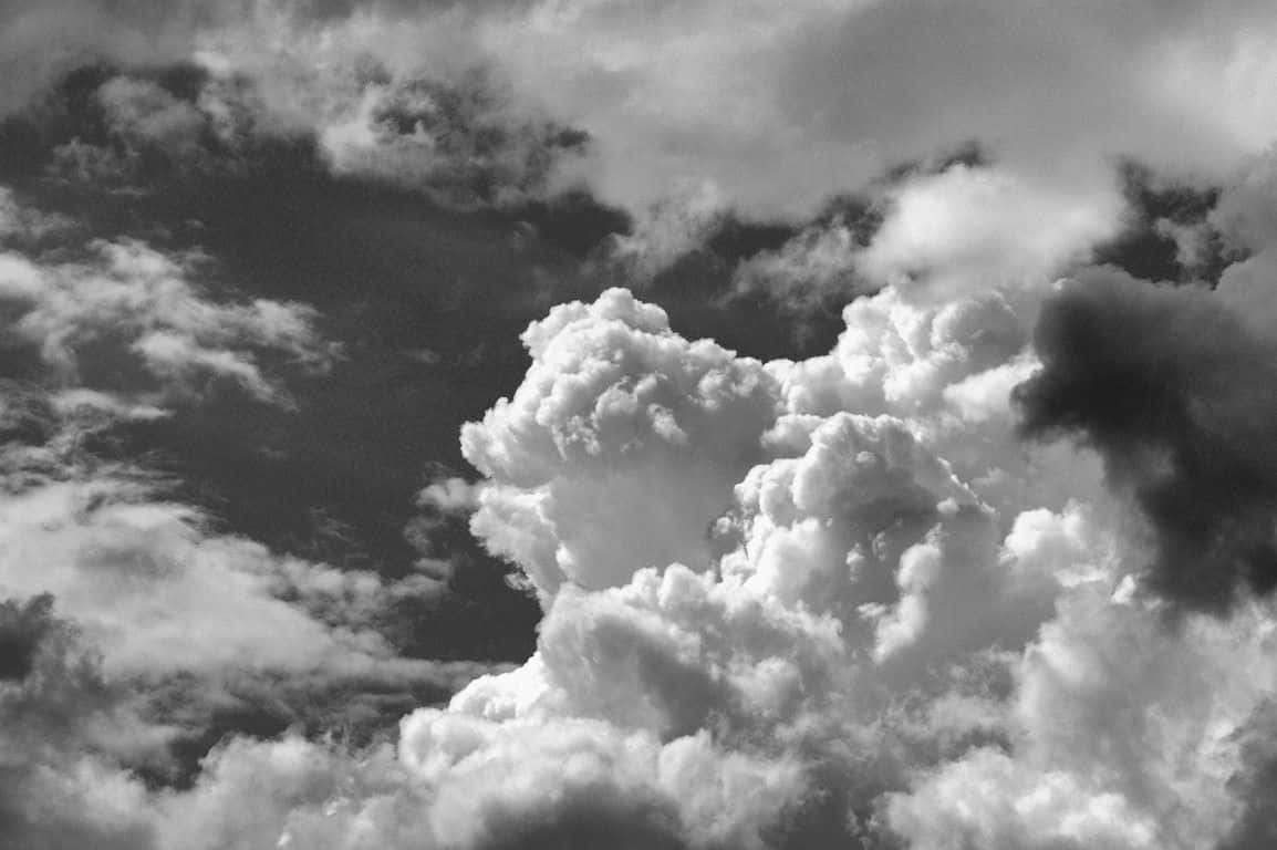 Black And White Sky 桌布 壁紙 — 戲劇性的單色雲朵，帶有紋理的山峰和深沉的陰影，營造出陰鬱的天空場景。