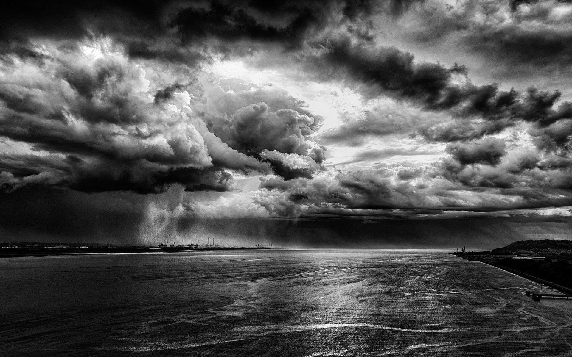 Black And White Storm 桌布 壁紙 — 戲劇性的單色風暴雲籠罩在廣闊的水域上，雨在地平線落下。