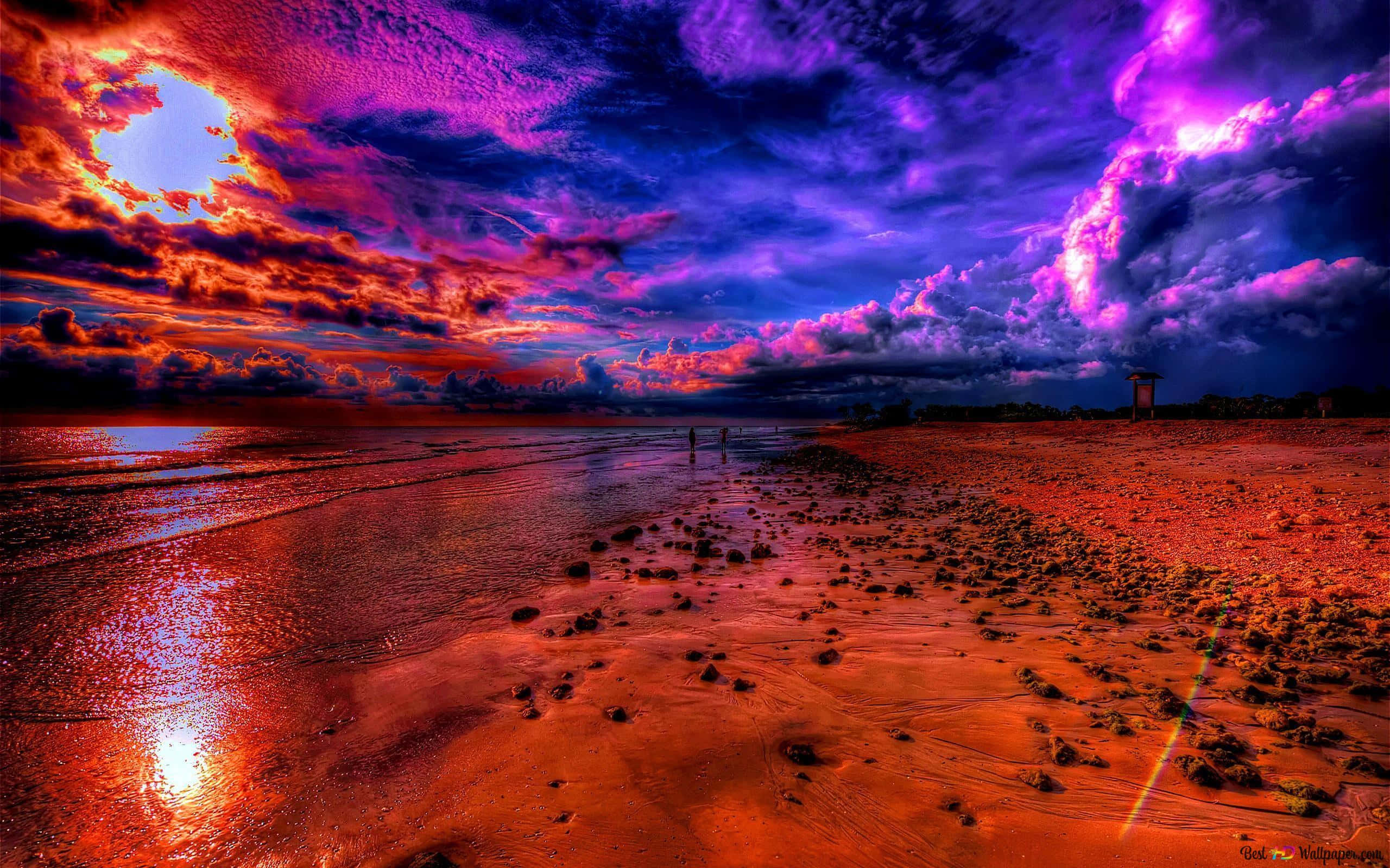 桌布 壁紙 — 戲劇性的夕陽將海灘染成火紅和深紫色，海浪在暴風雨的天空下拍打著海岸。