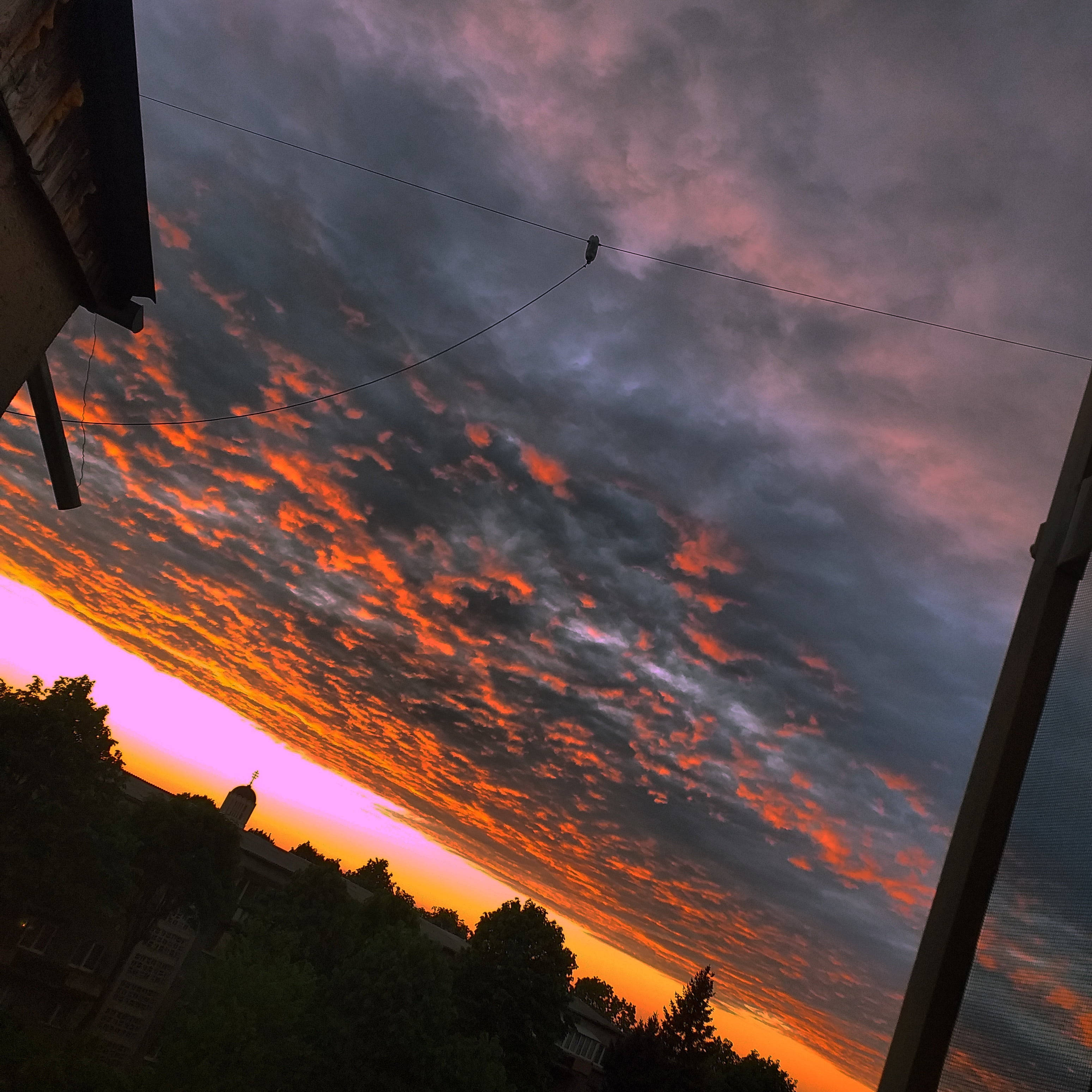 Aesthetic Sunset 桌布 壁紙 — 戲劇性的夕陽將雲彩染成火橙色和紫色，一隻鳥棲息在電線上，映襯著暮色天空。