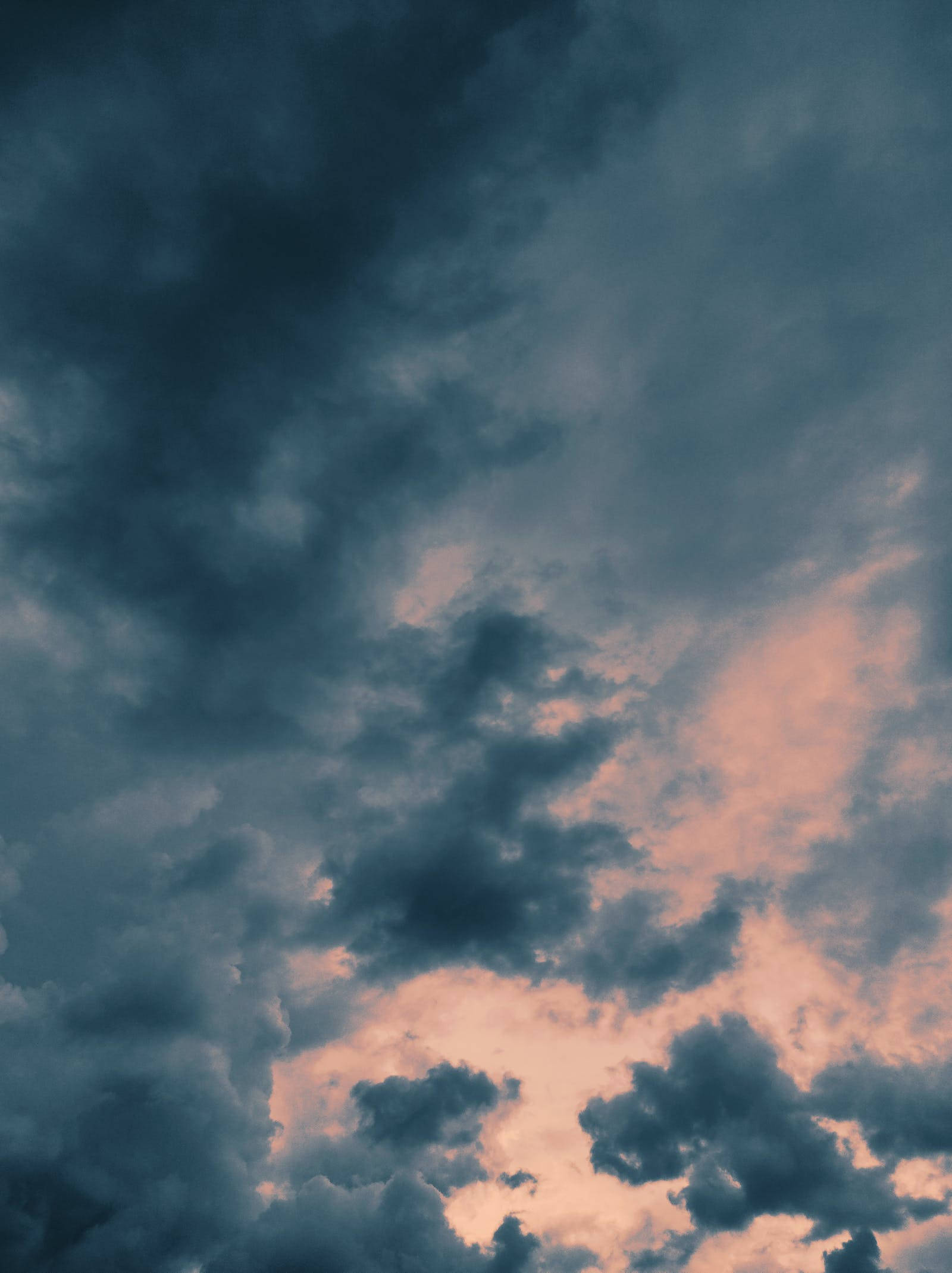 雲朵 桌布 壁紙 — 戲劇性的天空，深色暴風雲被柔和粉紅和橙色日落色調穿透。