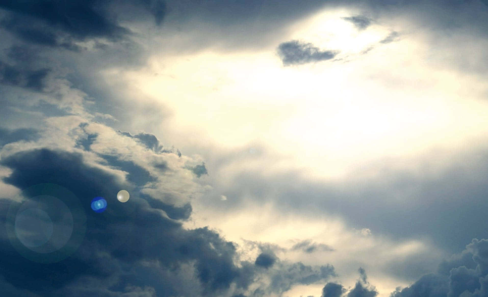 Heaven Clouds 桌布 壁紙 — 戲劇性的天空，烏雲被明亮的陽光分開，產生鏡頭光暈和柔和的金色光芒。