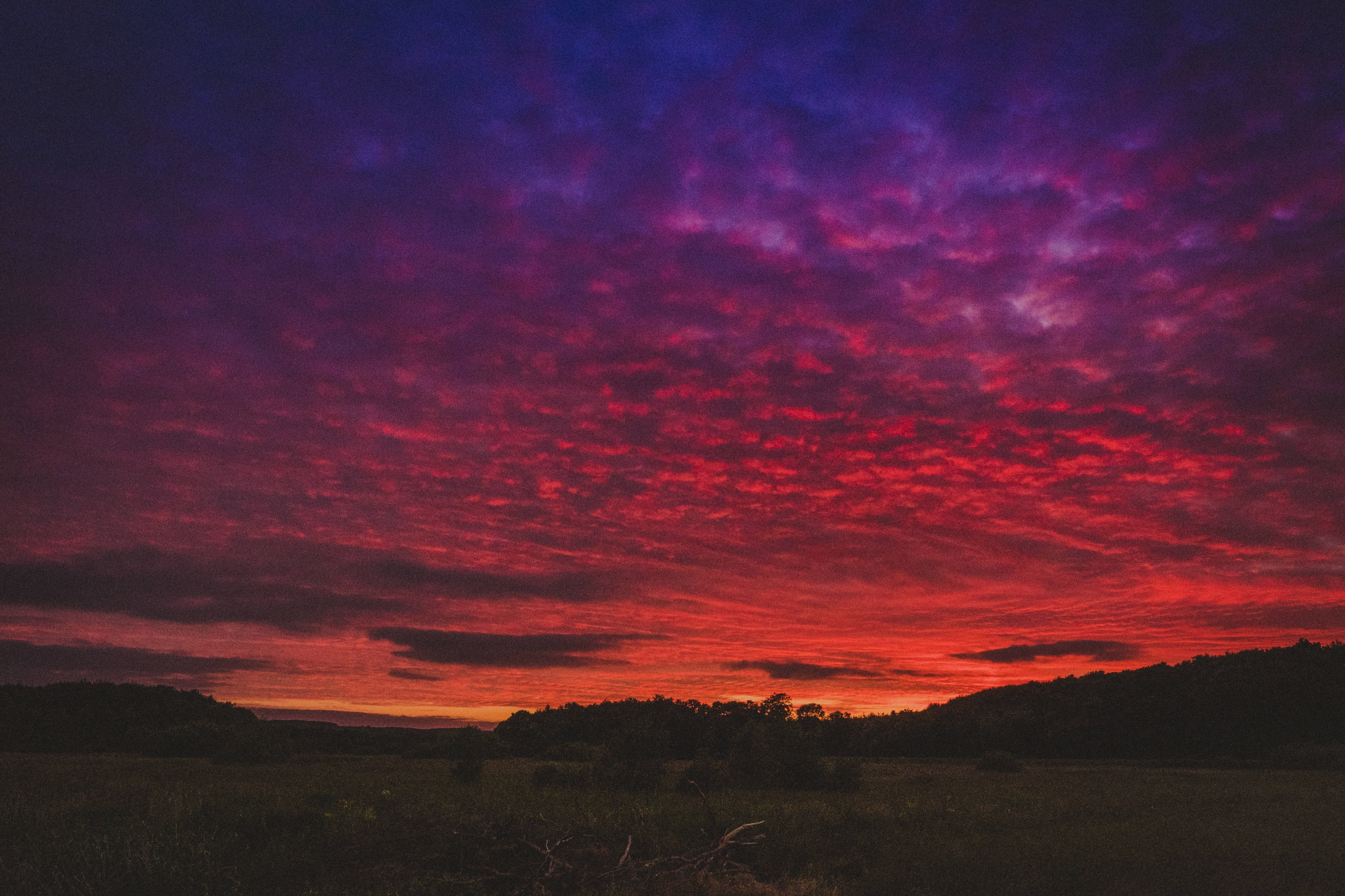 Beautiful Sky 桌布 壁紙 — 戲劇性的日落以火紅和深紫色渲染天空，映襯著黑暗的剪影景觀。