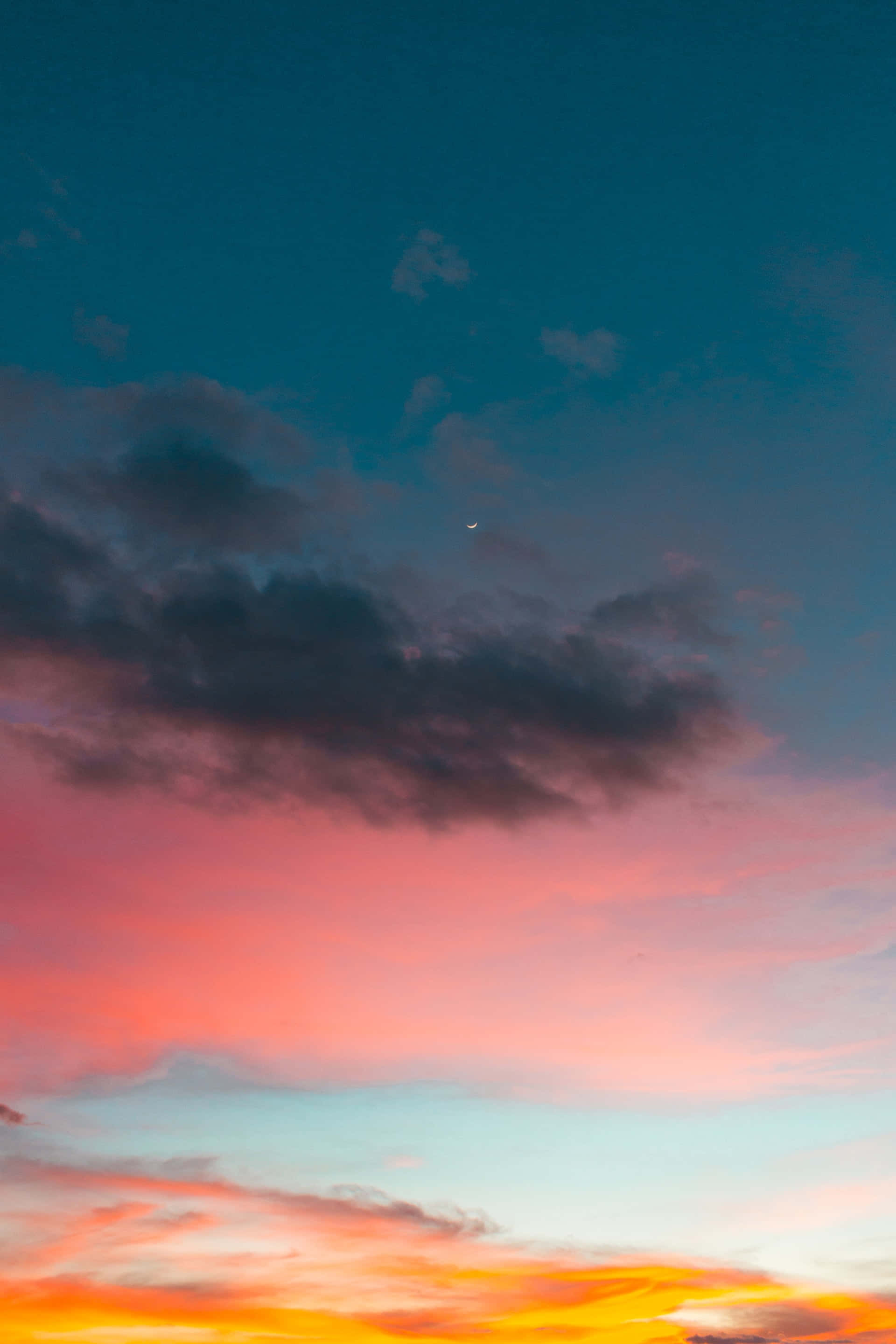 Colorful Sunset 桌布 壁紙 — 戲劇性的日落天空，火橙色雲朵融合成粉紅色和藍綠色，在黑暗的暴風雲之上，有一彎新月。