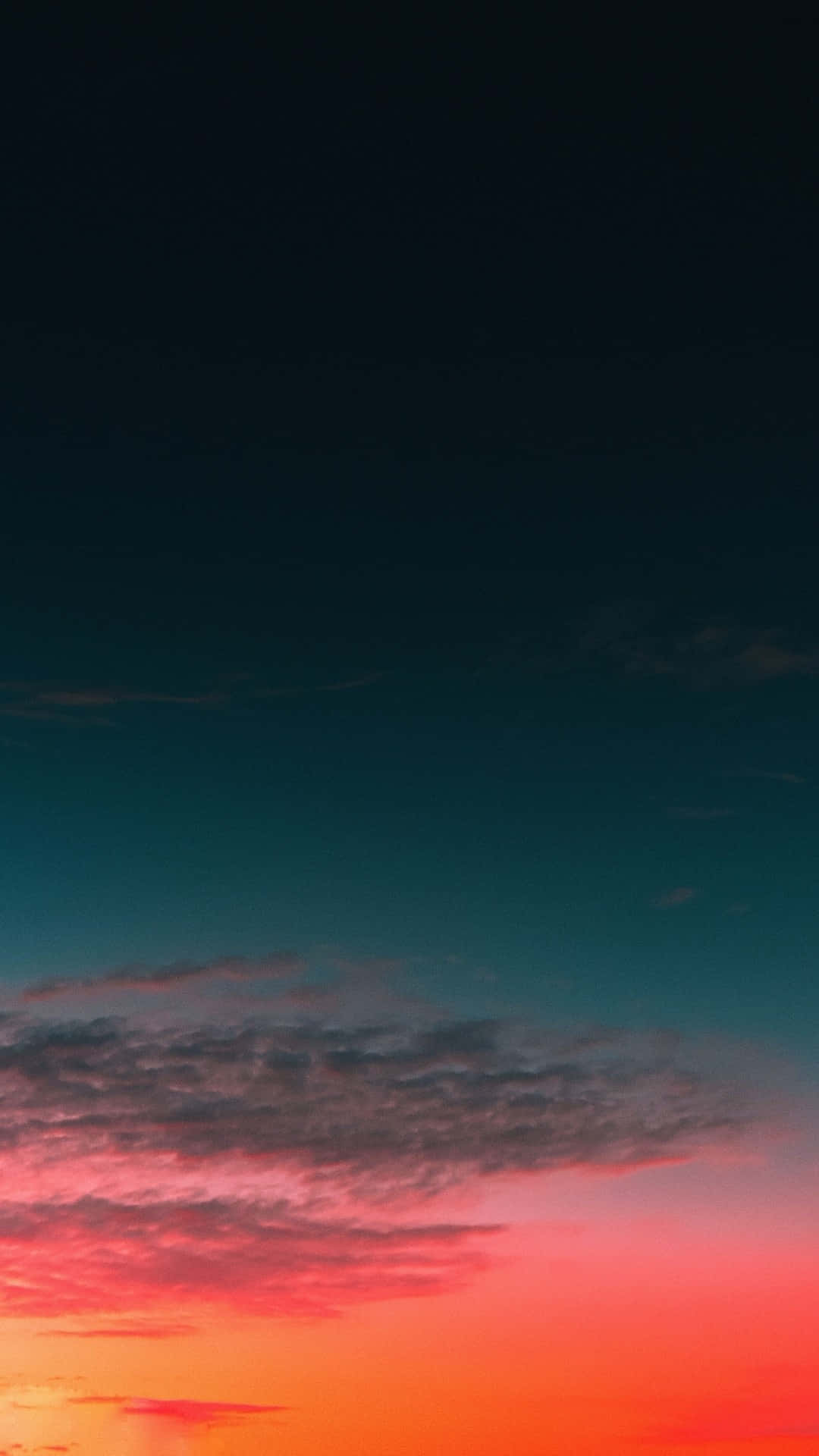 Calming iPhone 桌布 壁紙 — 戲劇性的日落天空從火熱的橙色過渡到深青色，縷縷雲彩在暮色中閃耀。