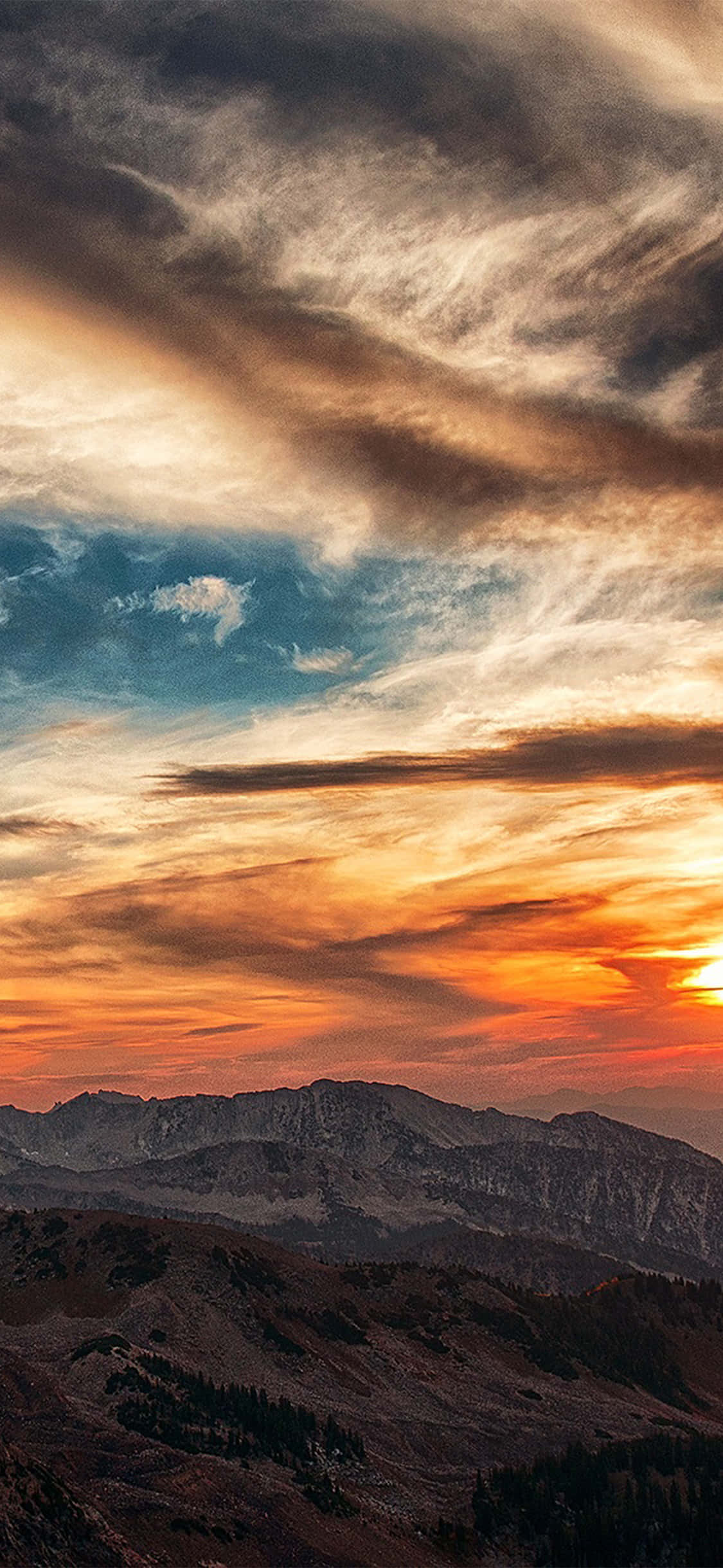 Clouds Aesthetics 桌布 壁紙 — 戲劇性的日落將天空染成火橙色和深藍色，映襯著崎嶇的山峰。