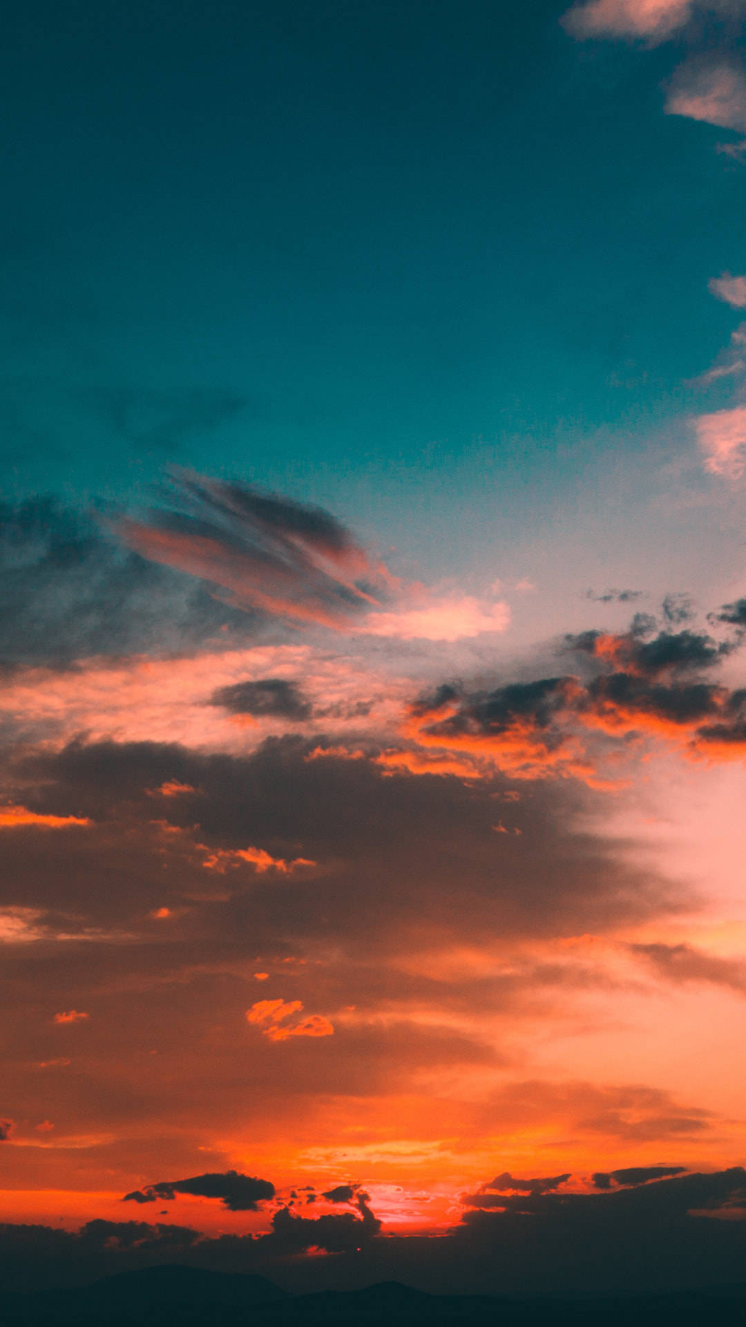 Cloud Aesthetic 桌布 壁紙 — 戲劇性的日落將天空染成火熱的橙色和深青色，雲朵在漸暗的地平線上發光。