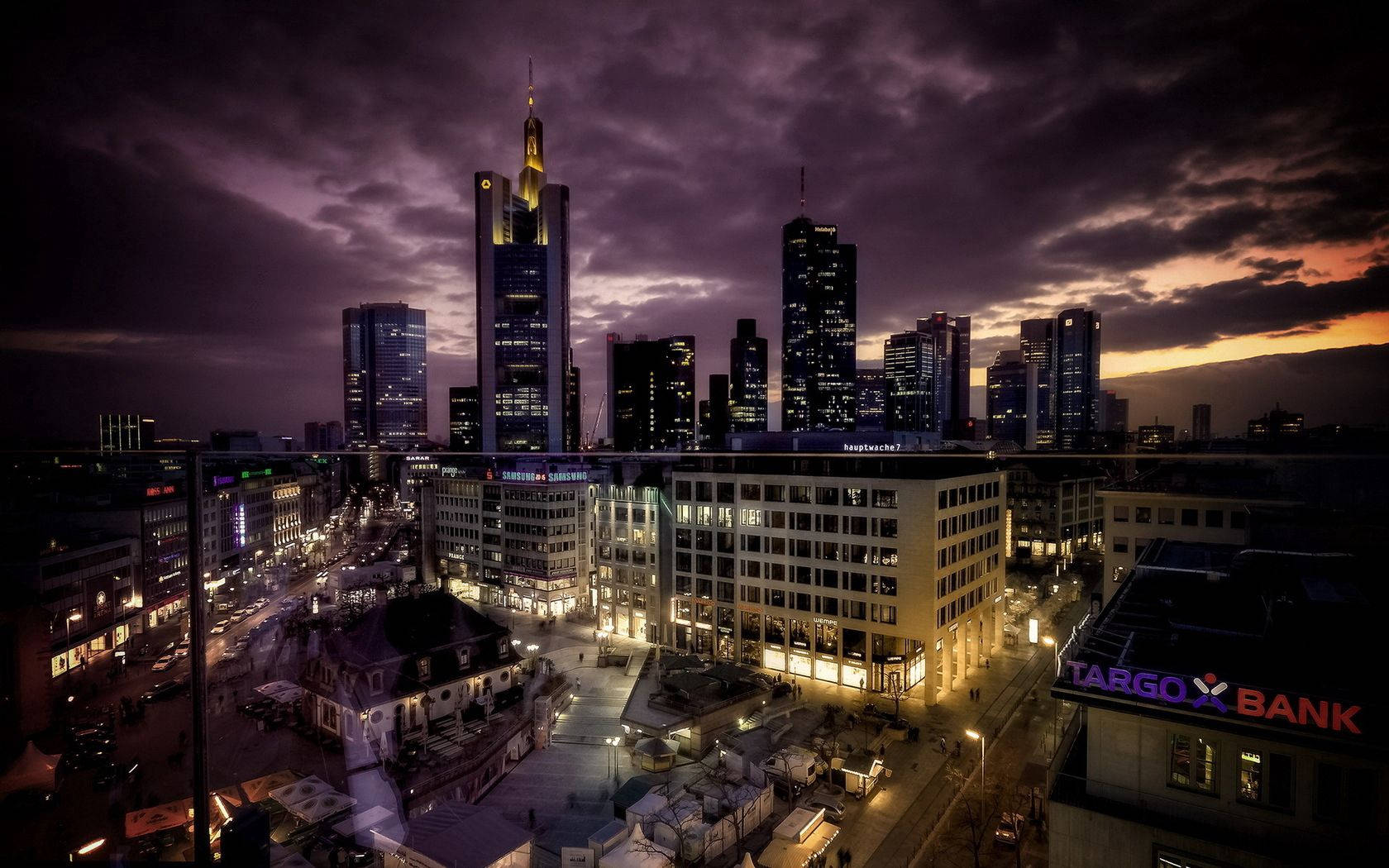 城市 桌布 壁紙 — 戲劇性的暮色城市景觀，高聳的摩天大樓在紫色和橙色的天空下閃耀。