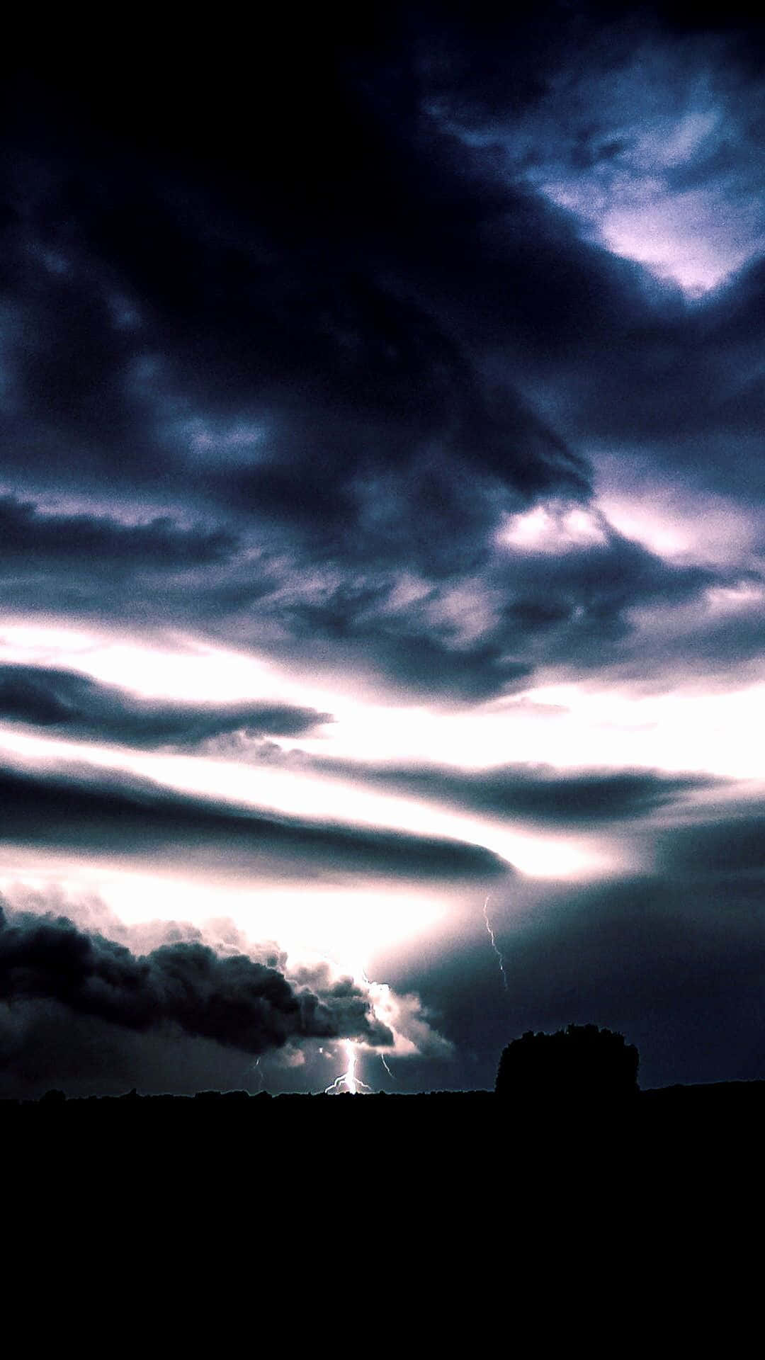 桌布 壁紙 — 戲劇性的暴風雨天空，生動的閃電照亮剪影地平線上的烏雲。