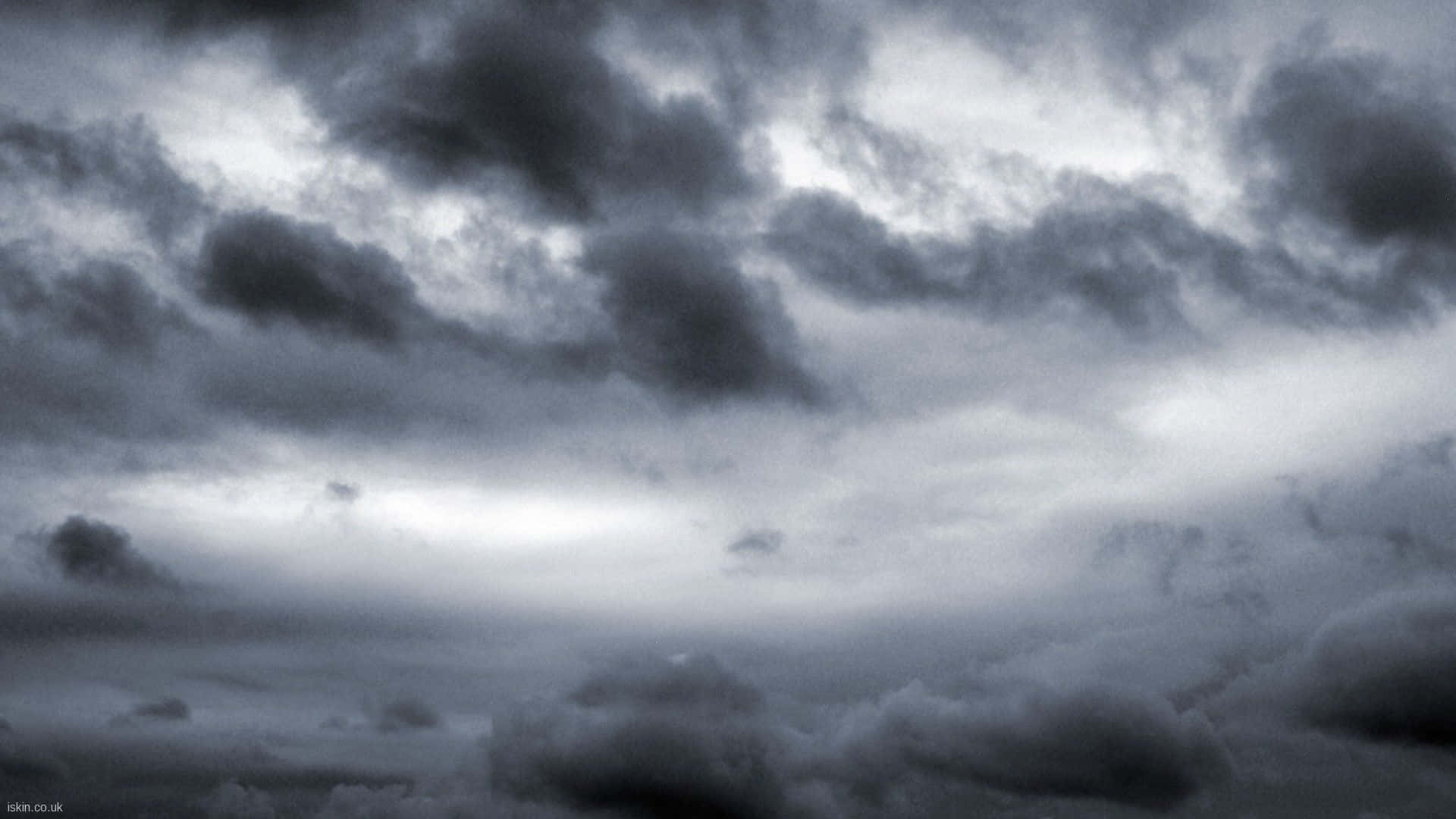 雲朵 桌布 壁紙 — 戲劇性的暴風雲在陰鬱的灰色天空中翻騰，明亮的陽光斑塊穿透雲層。