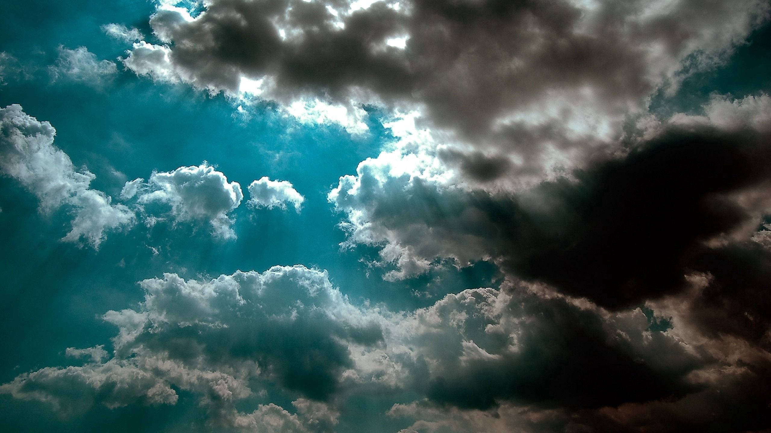 Azure 桌布 壁紙 — 戲劇性的暴風雲層，陽光穿透青綠色的天空，營造出陰鬱而強大的氛圍。