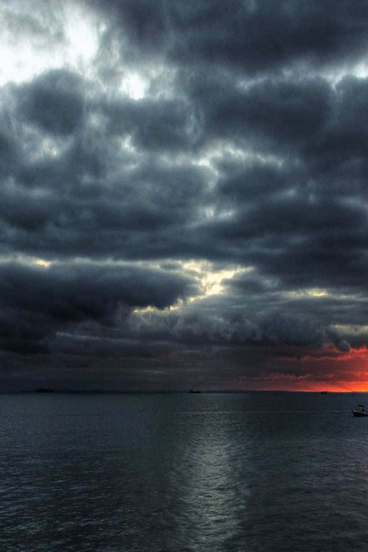 Weather 桌布 壁紙 — 戲劇性的暴風雲籠罩著平靜的海面，熾熱的日落色調從地平線滲透出來。