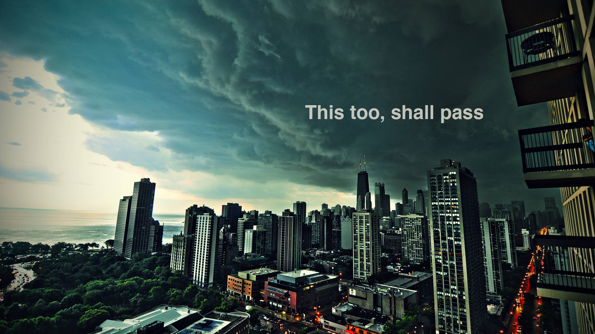Motivational Aesthetic Desktop 桌布 壁紙 — 戲劇性的暴風雲籠罩著黃昏的城市景觀，閃爍的路燈和遠處的湖泊。