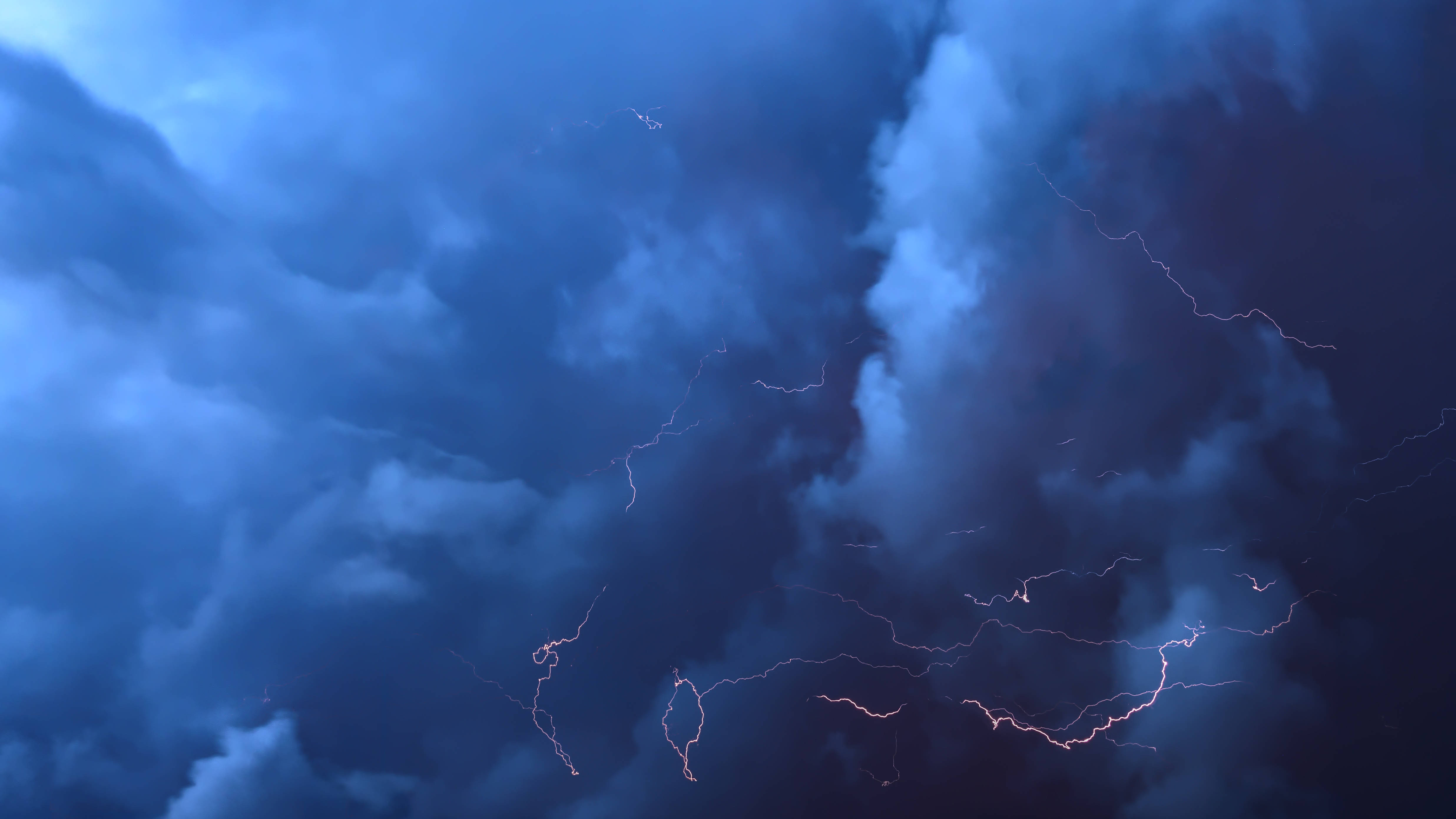 閃電 桌布 壁紙 — 戲劇性的暴風雲被鋸齒狀閃電照亮，在動盪的天空中劈啪作響。