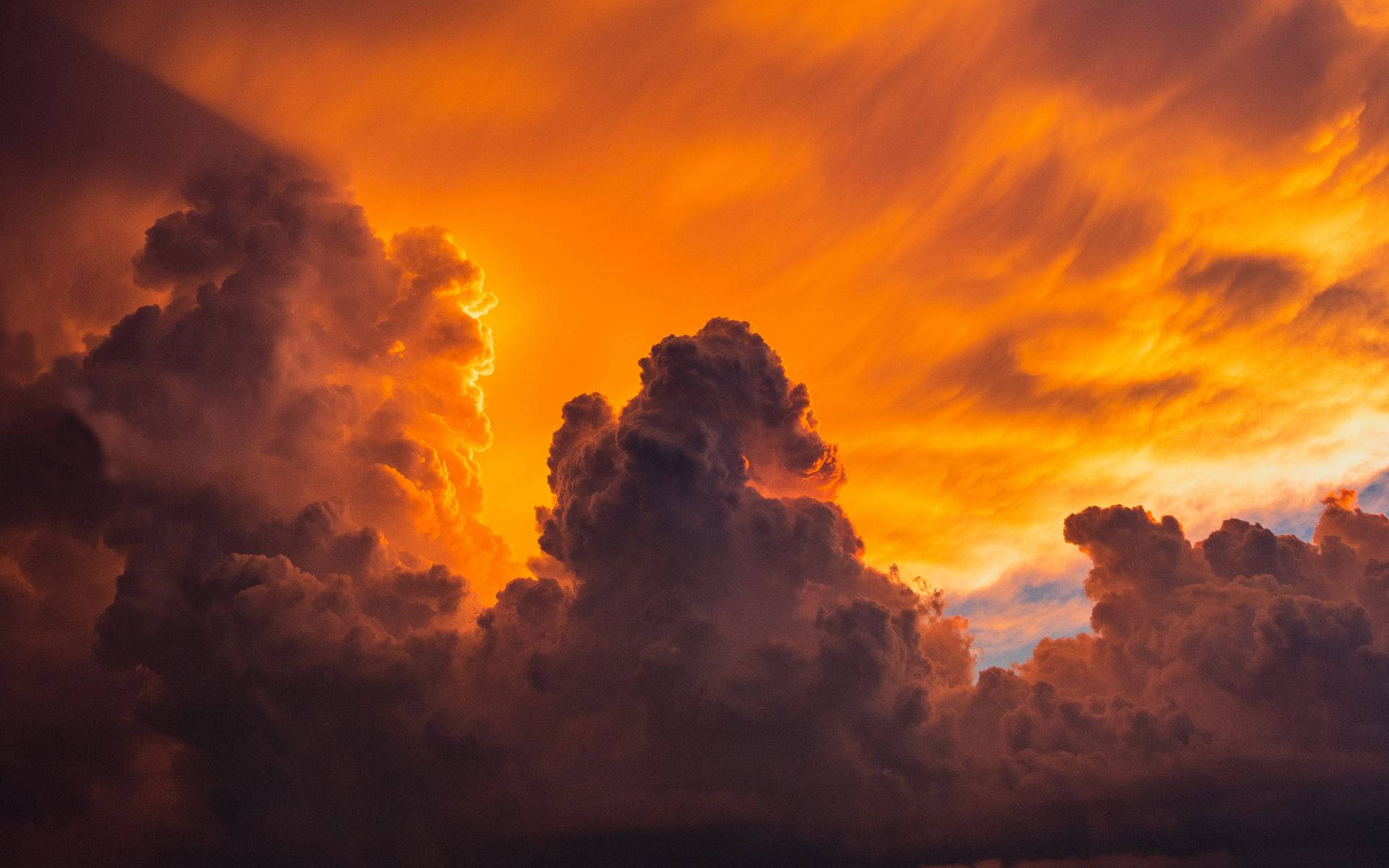 夕陽天空 桌布 壁紙 — 戲劇性的橙色和紫色暴風雲，被發光的日落照亮，天空中可見閃電劃過。