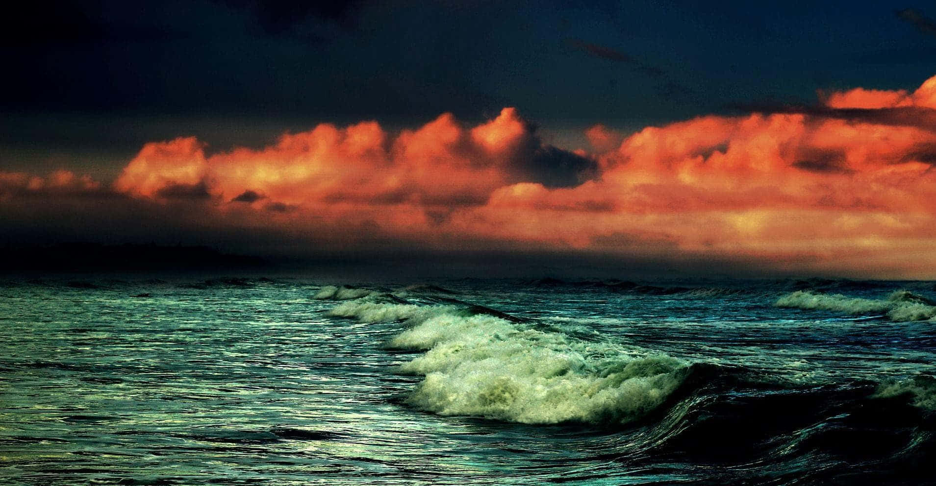 Creepy Ocean 桌布 壁紙 — 戲劇性的海浪在熾熱的橙色和深藍色日落天空下翻騰。