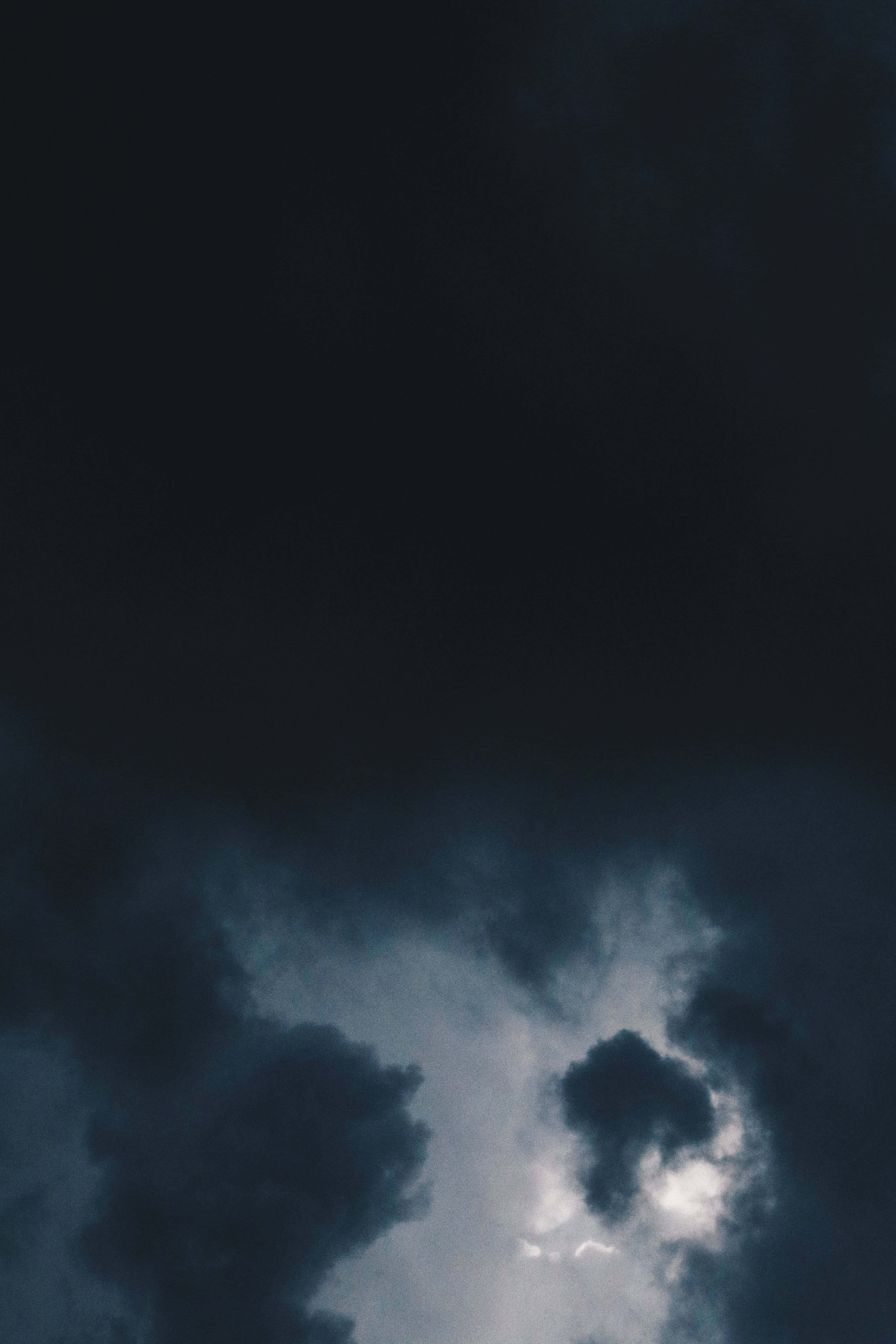 Black Clouds 桌布 壁紙 — 戲劇性的烏雲翻滾，一道明亮的光線穿透陰鬱的天空。