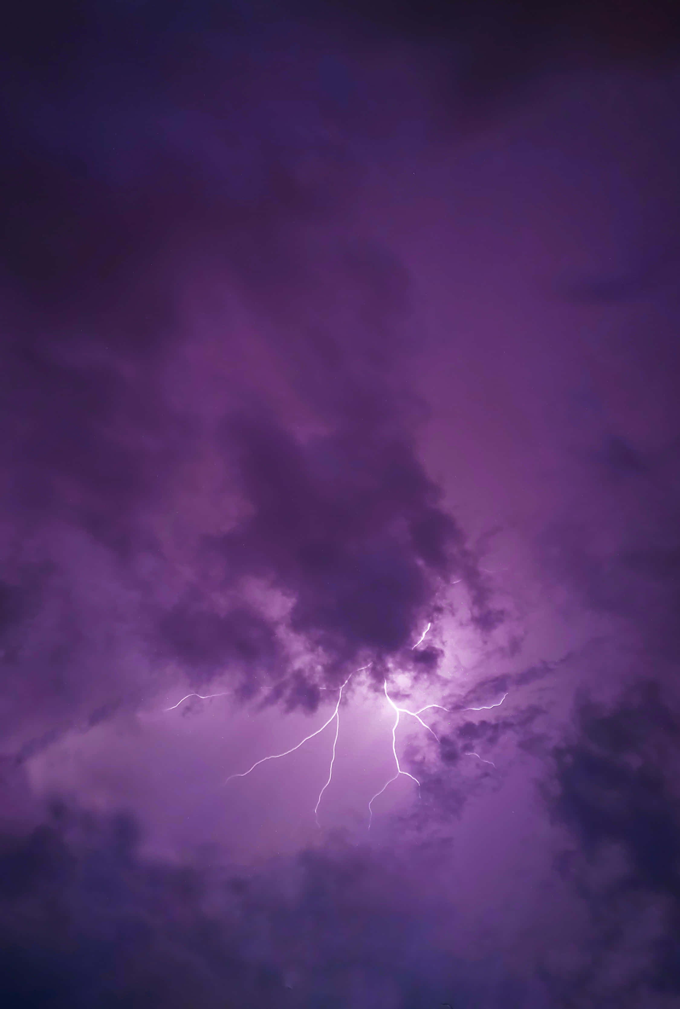 Lightning Bolt 桌布 壁紙 — 戲劇性的紫色暴風雨天空，被鋸齒狀的白色閃電劈開濃密雲層照亮。