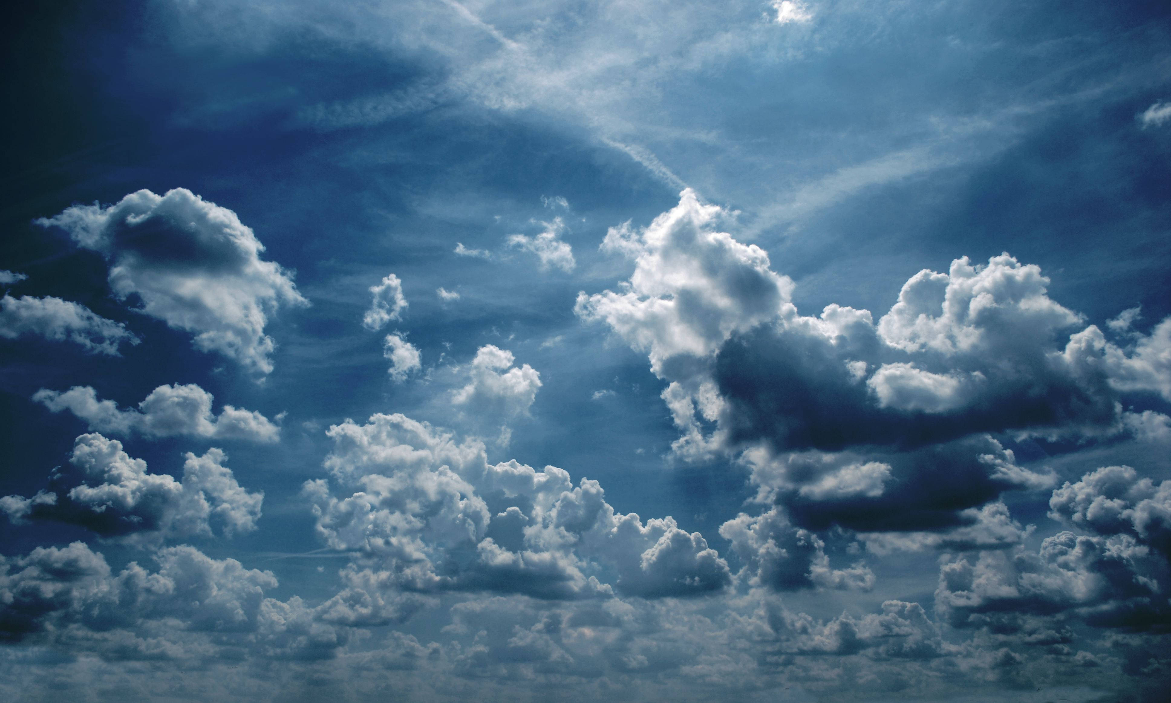 天空 桌布 壁紙 — 戲劇性的藍天，充滿蓬鬆的白雲，在明亮的陽光下投射出柔和的陰影。