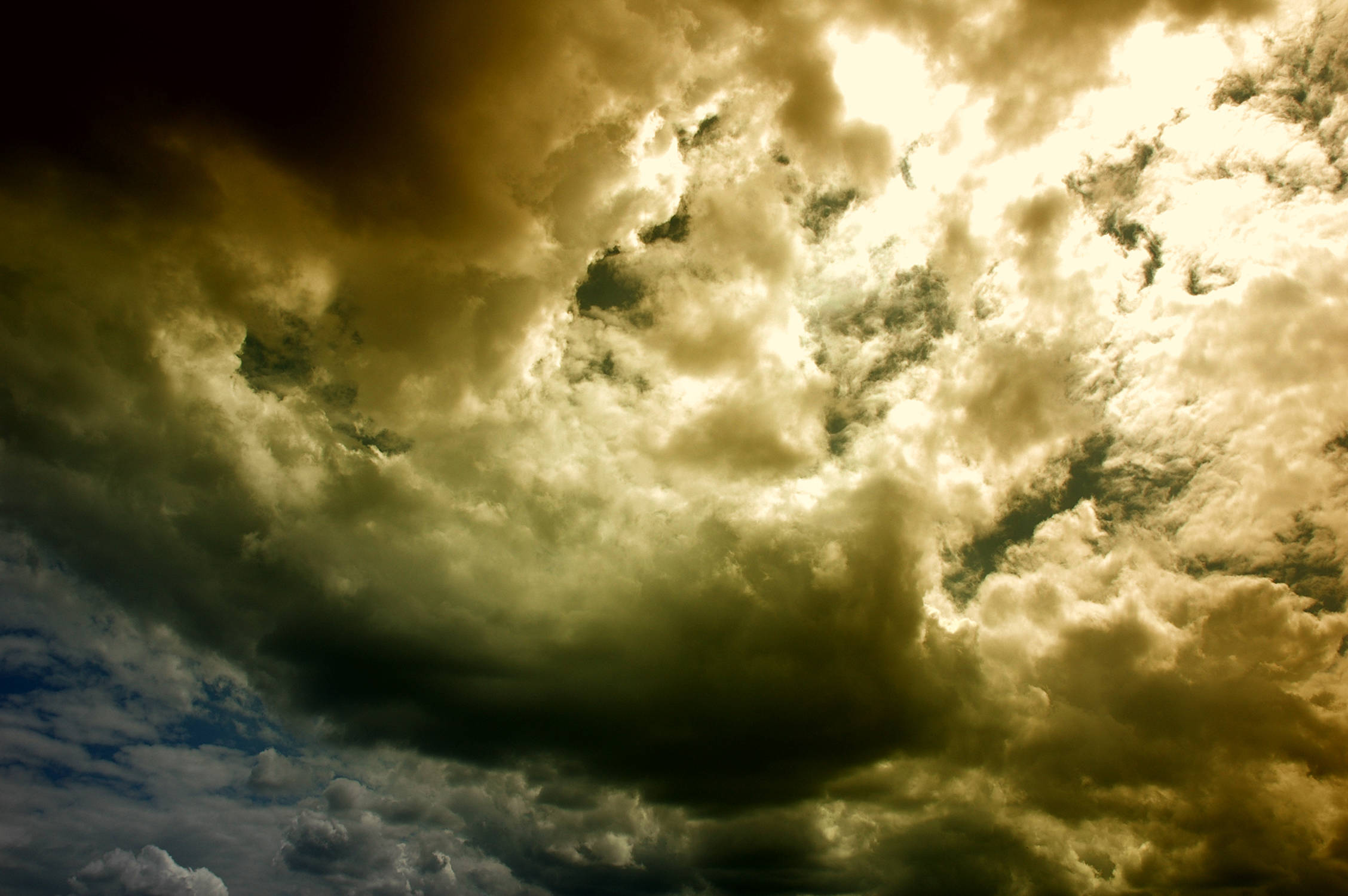 Beautiful Sky 桌布 壁紙 — 戲劇性的金色雲朵在黑暗的天空中旋轉，藍色隱約可見。