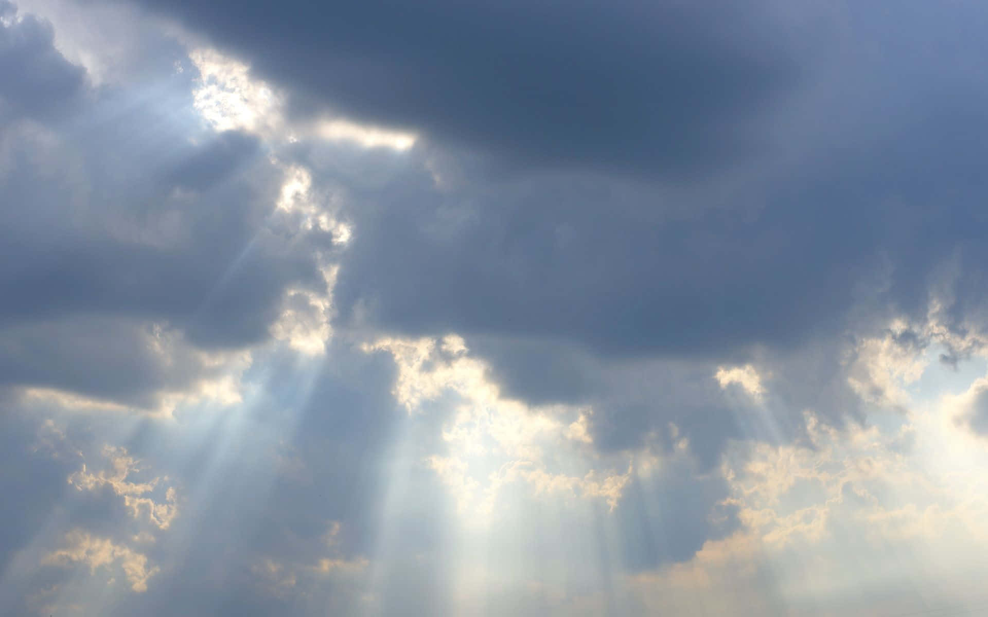 雲朵 桌布 壁紙 — 戲劇性的陽光穿透厚厚的烏雲，在陰沉天空中投射出金色光芒。
