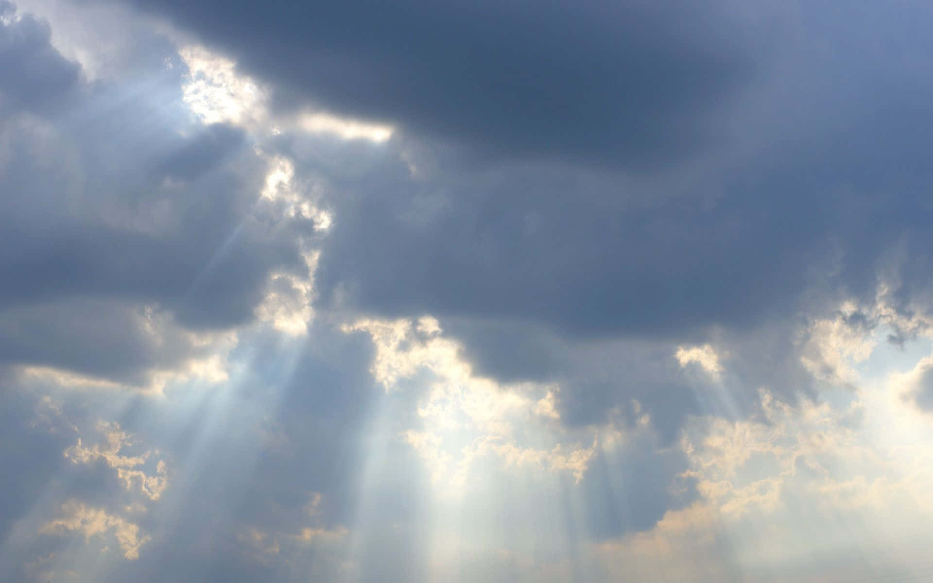 Cloudy Sky 桌布 壁紙 — 戲劇性的陽光穿透厚厚的烏雲，在陰沉的天際上投射出金色光束。