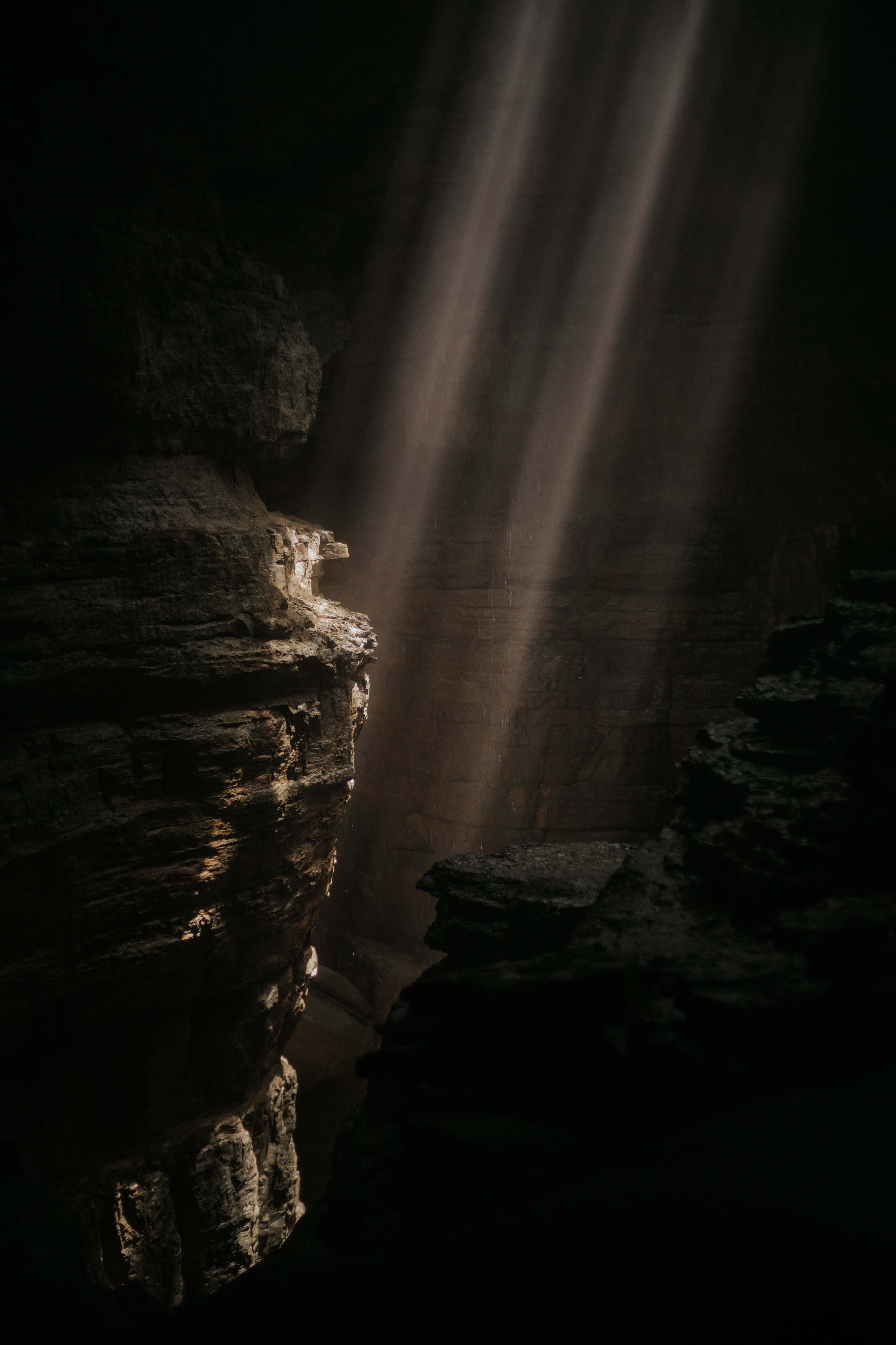 Cave 桌布 壁紙 — 戲劇性的陽光穿透黑暗峽谷，照亮崎嶇岩石形成強烈對比。