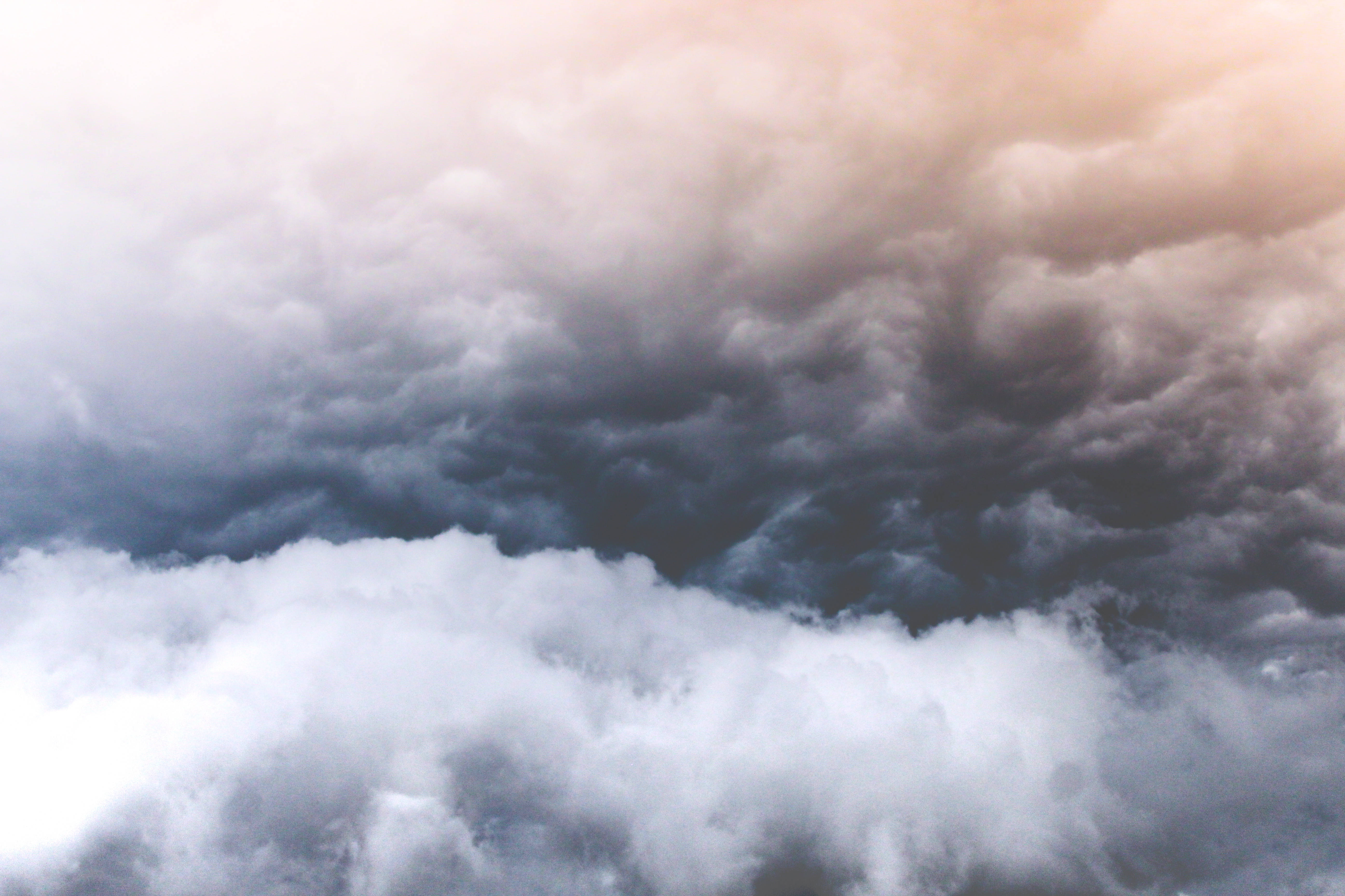 暴風 桌布 壁紙 — 戲劇性的雲在暴風雨的天空中旋轉，深灰色和白色的形態被上方溫暖的金色光芒照亮。