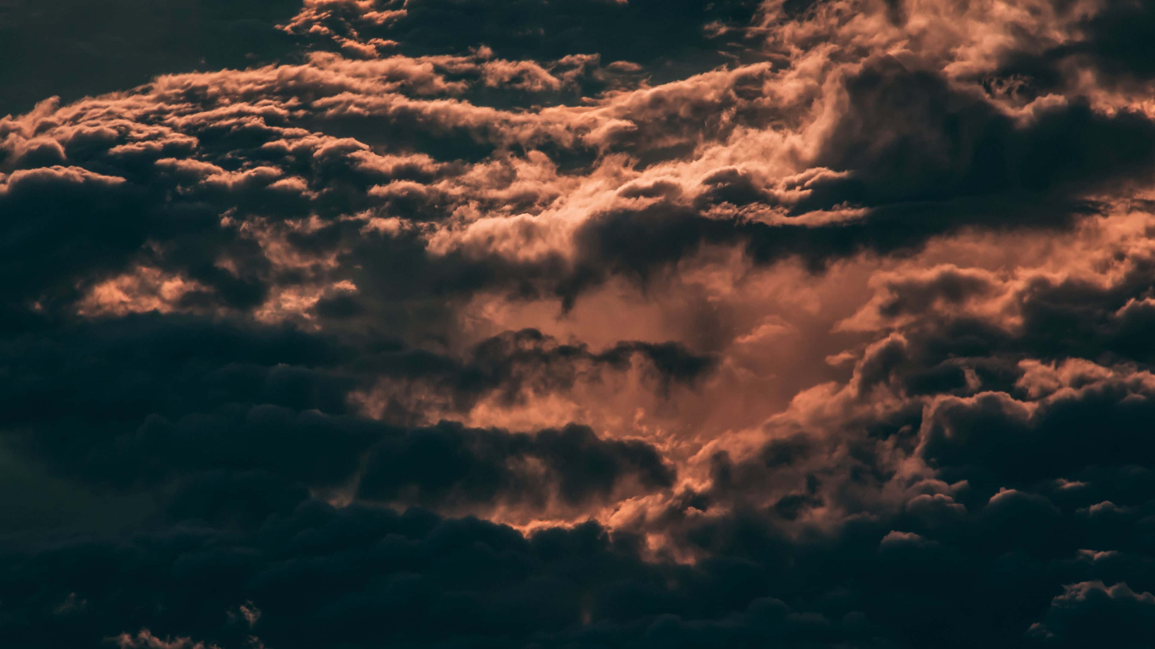Clouds Aesthetics 桌布 壁紙 — 戲劇性的雲彩在暮色天空中散發出火橙色和深沉的陰影。