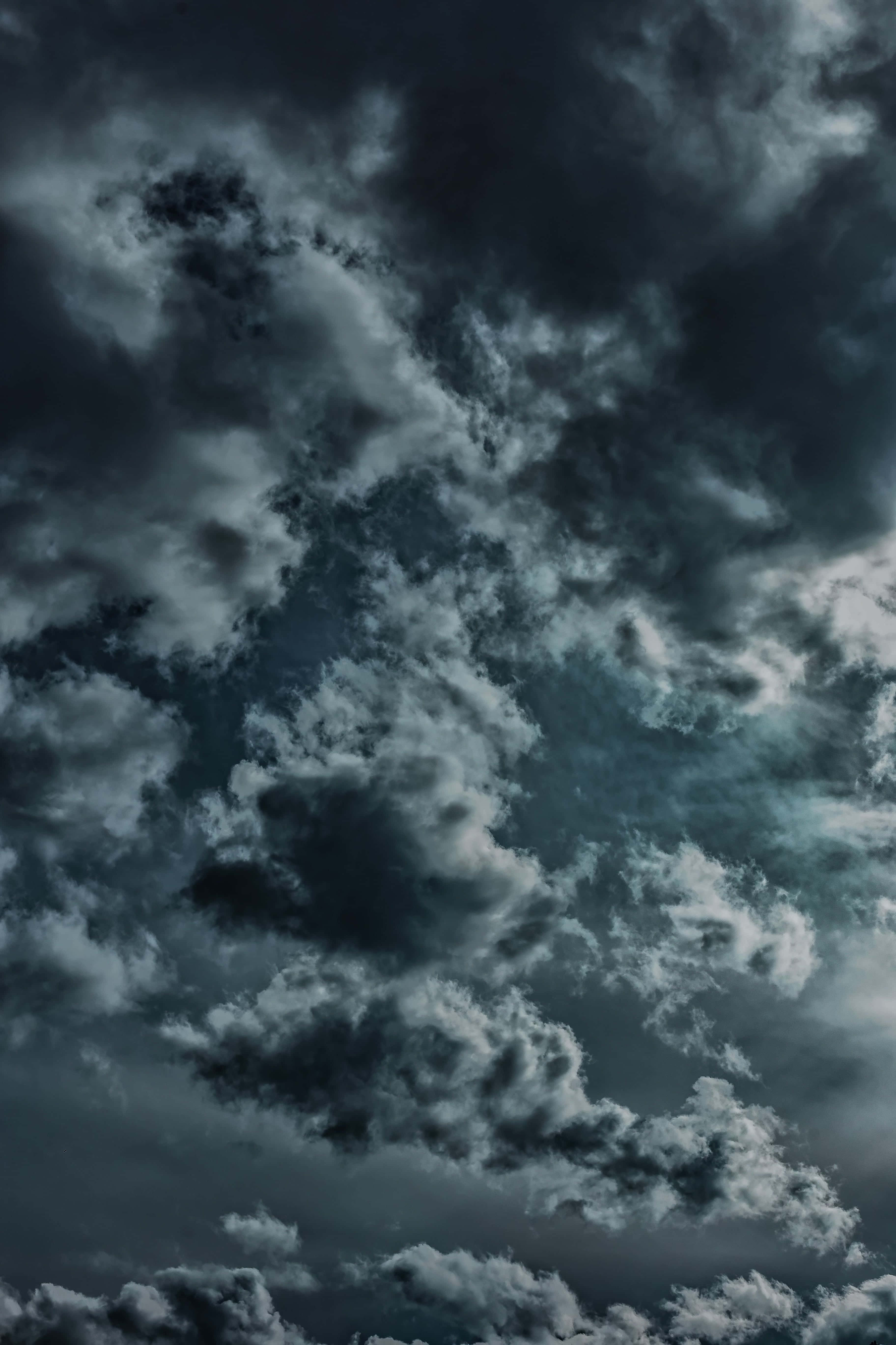 Cloudy Sky 桌布 壁紙 — 戲劇性的風暴雲在深灰和白色中旋轉，映襯著憂鬱的暮色天空。