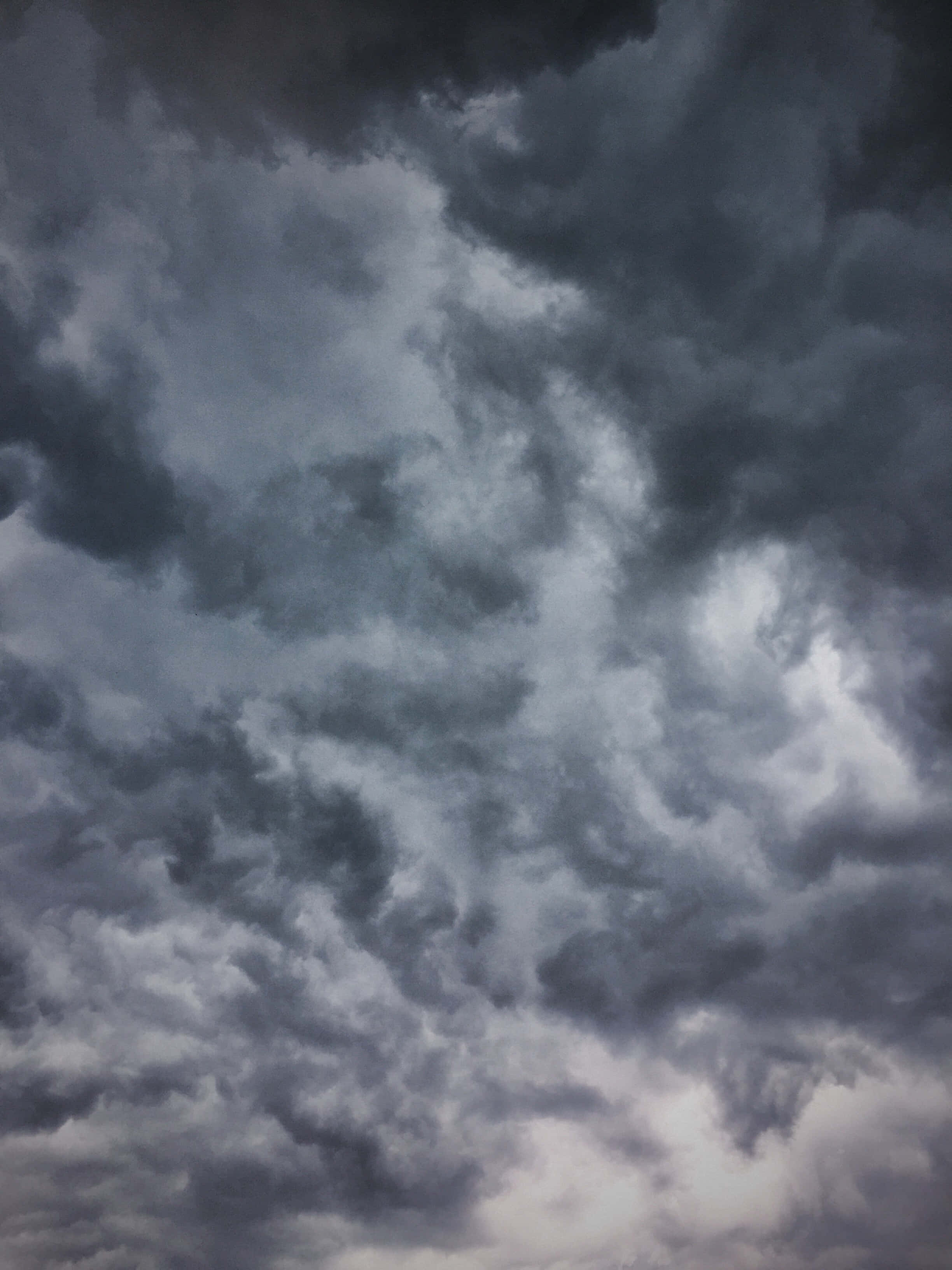 Cloudy 桌布 壁紙 — 戲劇性的風暴雲在深灰和白色中旋轉，籠罩在陰沉天空下。