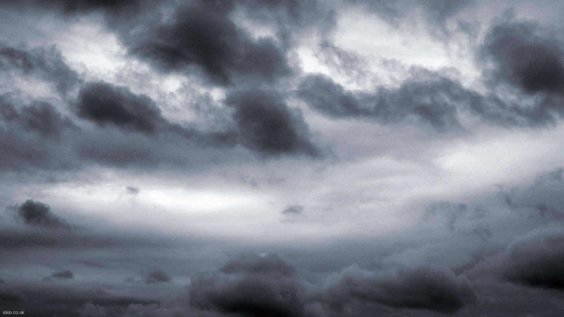 Stormy 桌布 壁紙 — 戲劇性的風暴雲在陰鬱的黑白天空中旋轉，有明亮的陽光斑塊穿透而出。