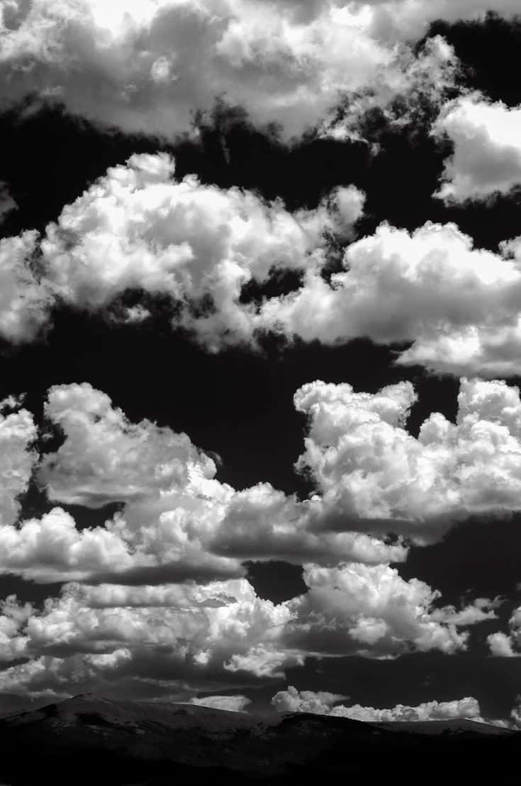 Black And White Sky 桌布 壁紙 — 戲劇性的高對比黑白雲層在暴風雨天空下聚集在黑暗山脈輪廓之上。
