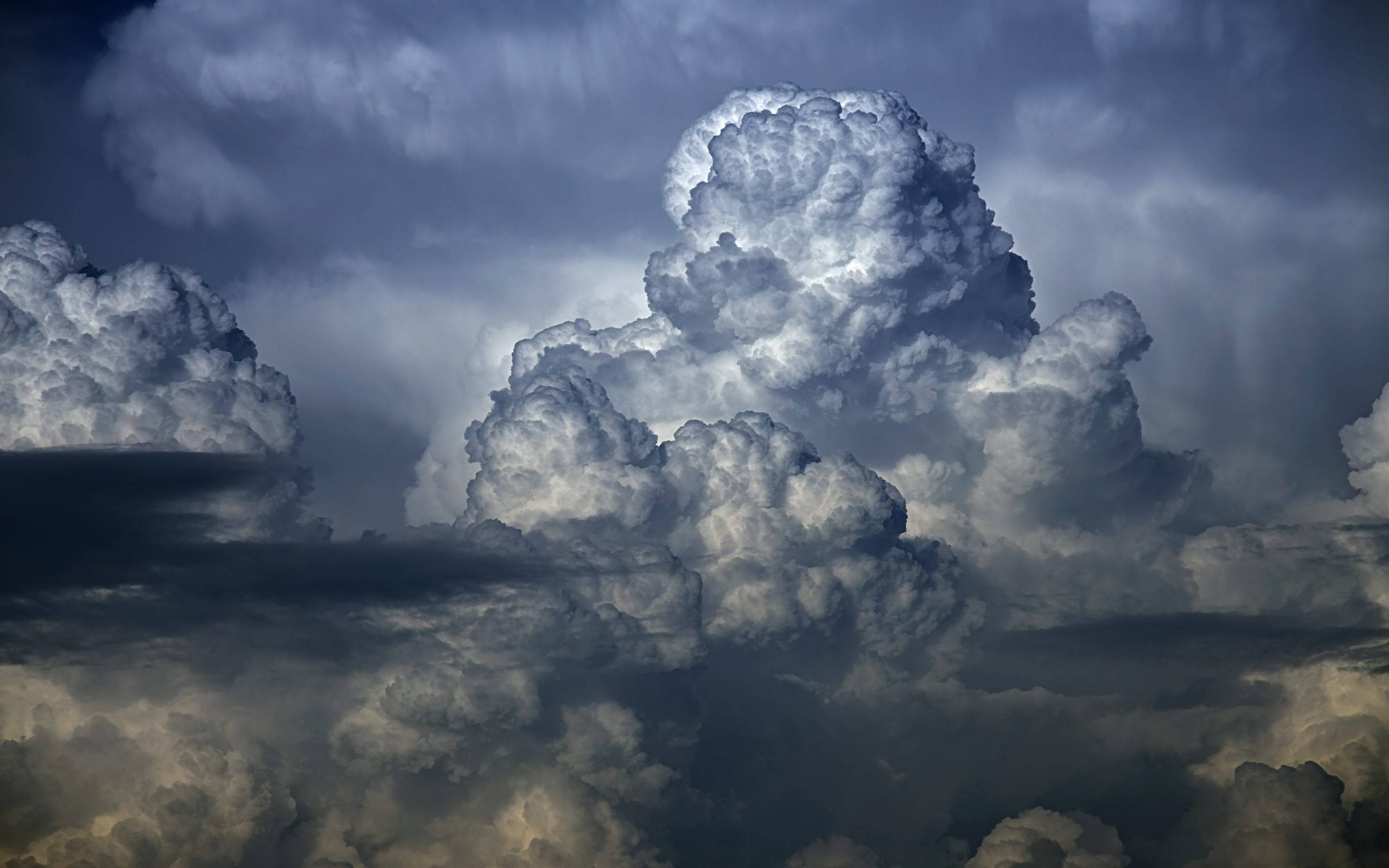 雲朵 桌布 壁紙 — 戲劇性的高聳積雨雲在陰暗的天空中被陽光照射。