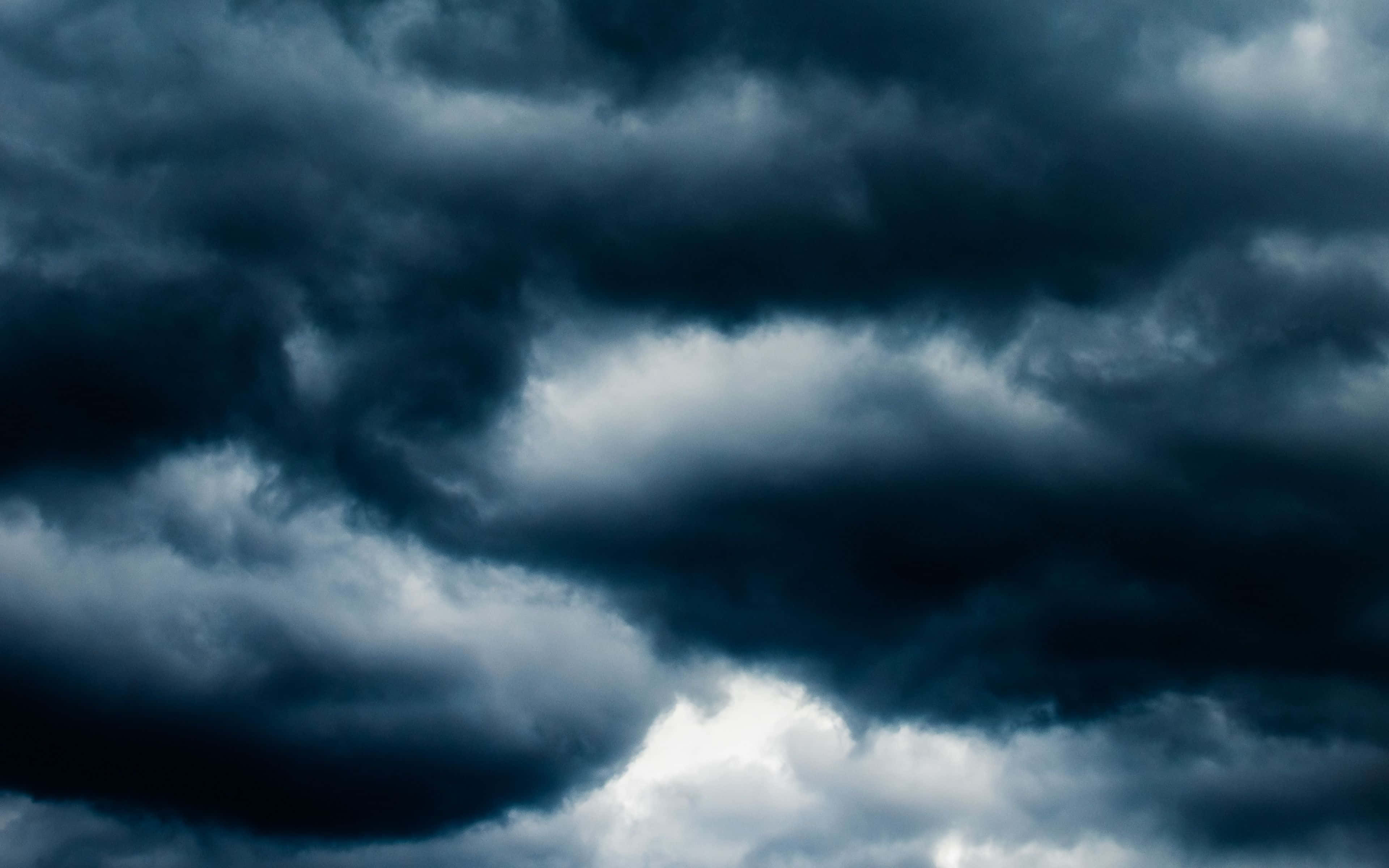 Cloudy Sky 桌布 壁紙 — 戲劇性的黑暗暴風雲在頭頂盤旋，明亮的閃電照亮了動盪的天空。