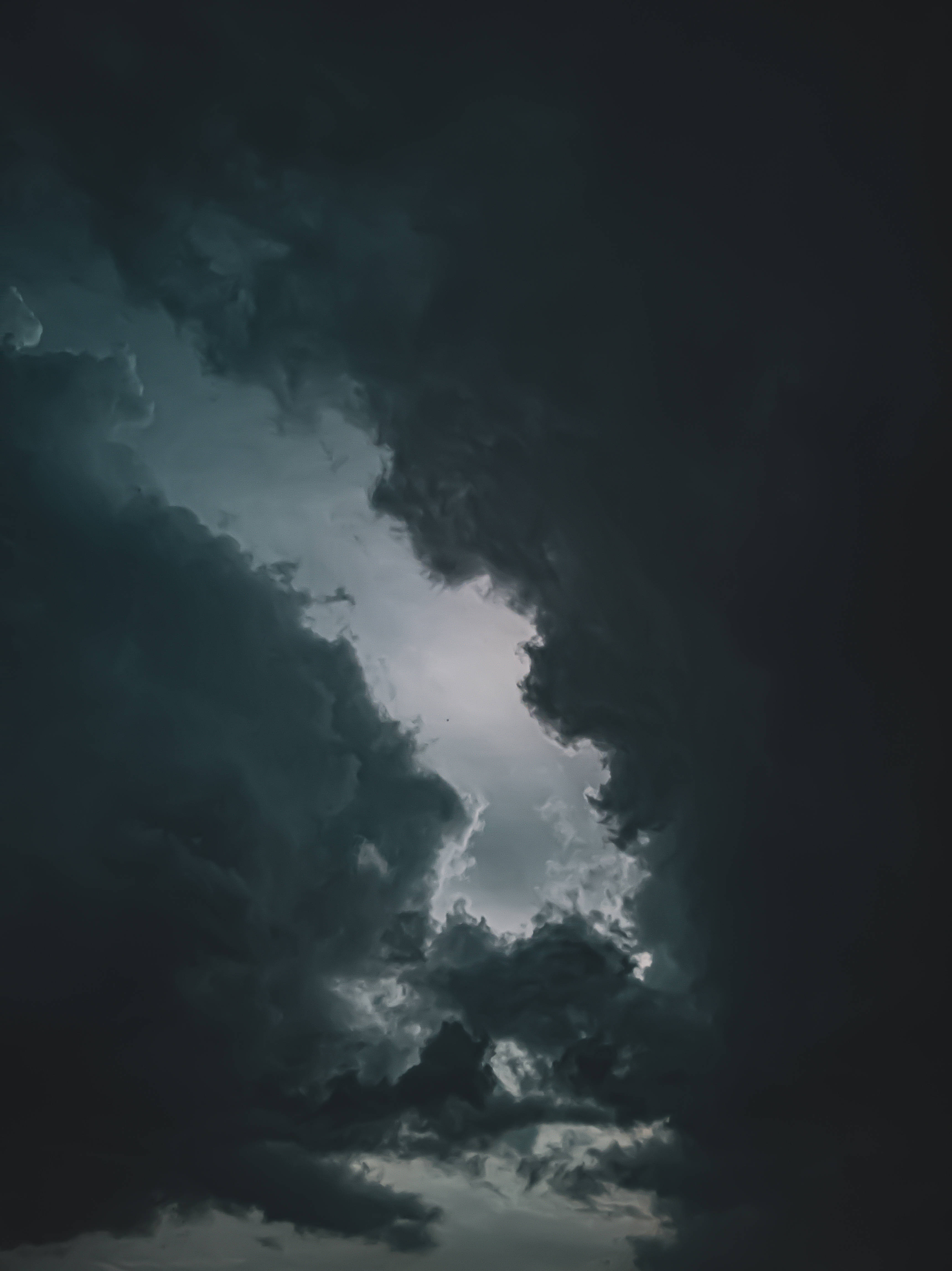Dim 桌布 壁紙 — 戲劇性的黑暗暴風雲散開，露出上方明亮發光的天空。