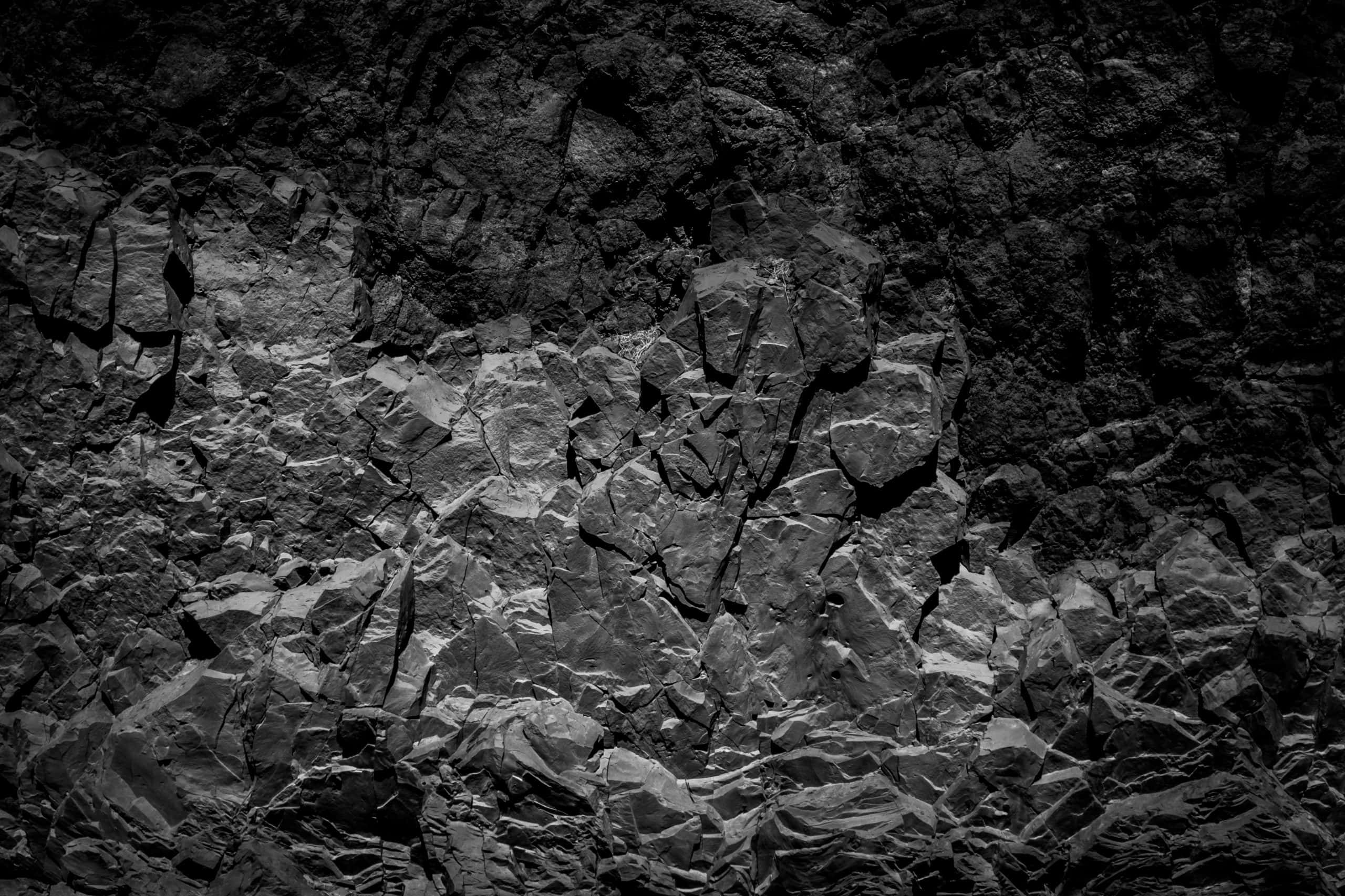 Dark Rock 桌布 壁紙 — 戲劇性的黑白特寫，呈現崎嶇紋理岩石結構，帶有深邃陰影和銳利高光。