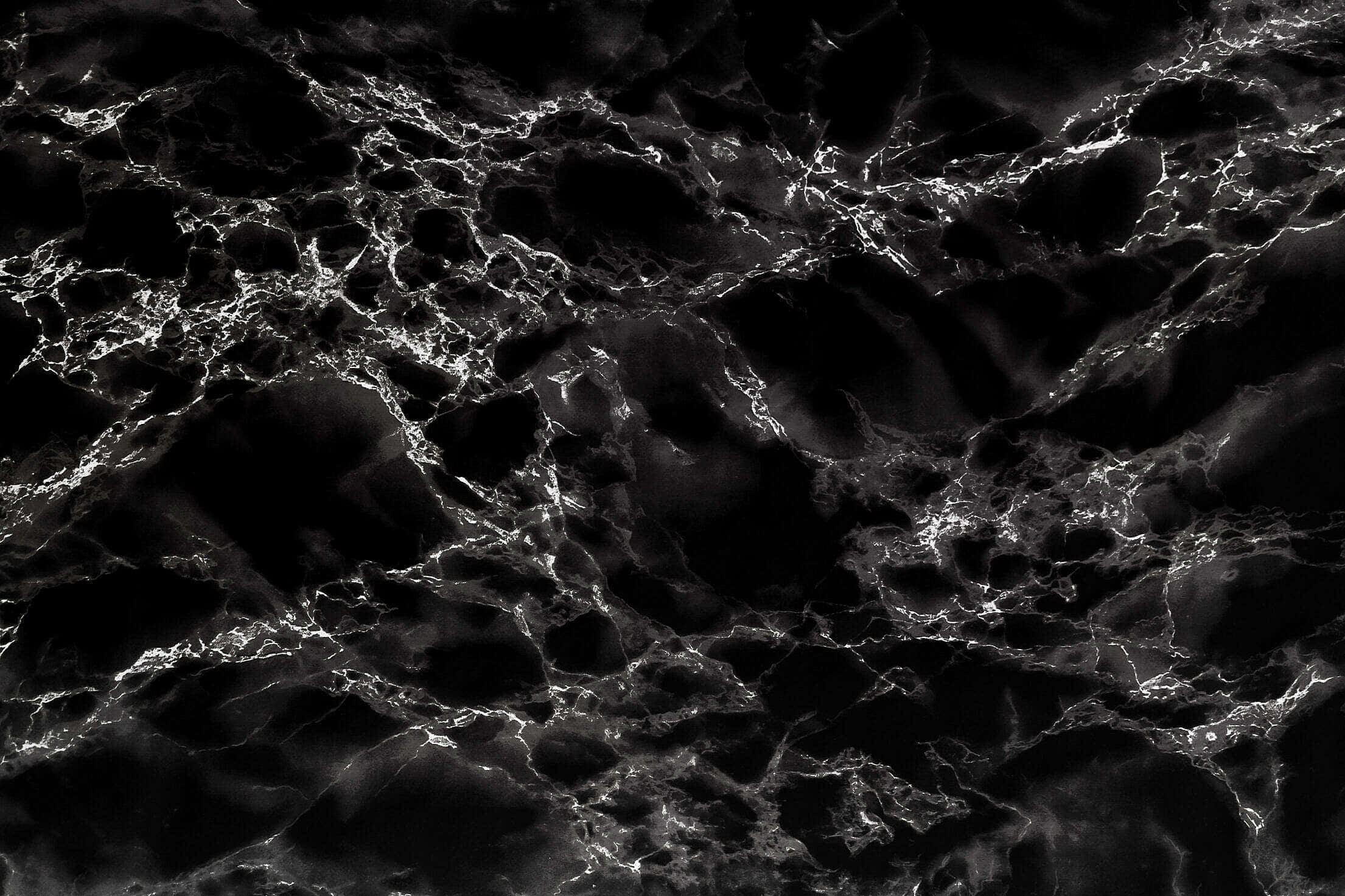 Black And White Marble 桌布 壁紙 — 戲劇性的黑色大理石表面，帶有發光的白色紋理，形成錯綜複雜的網狀圖案。