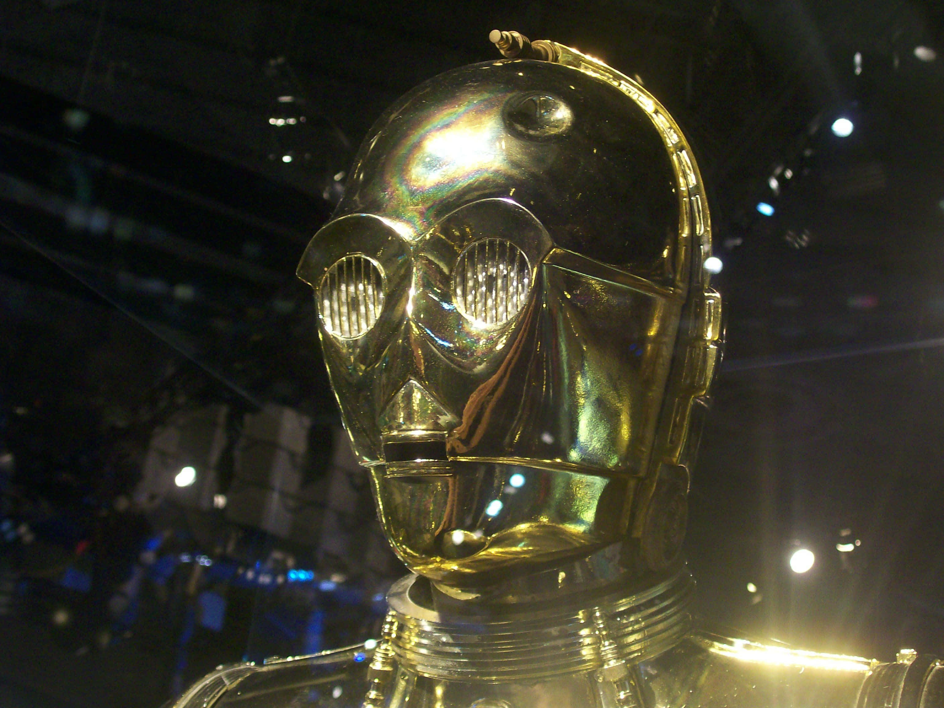 C-3po 桌布 壁紙 — 戲劇性舞台燈光下，閃亮金色機器人頭部特寫，眼睛發光。