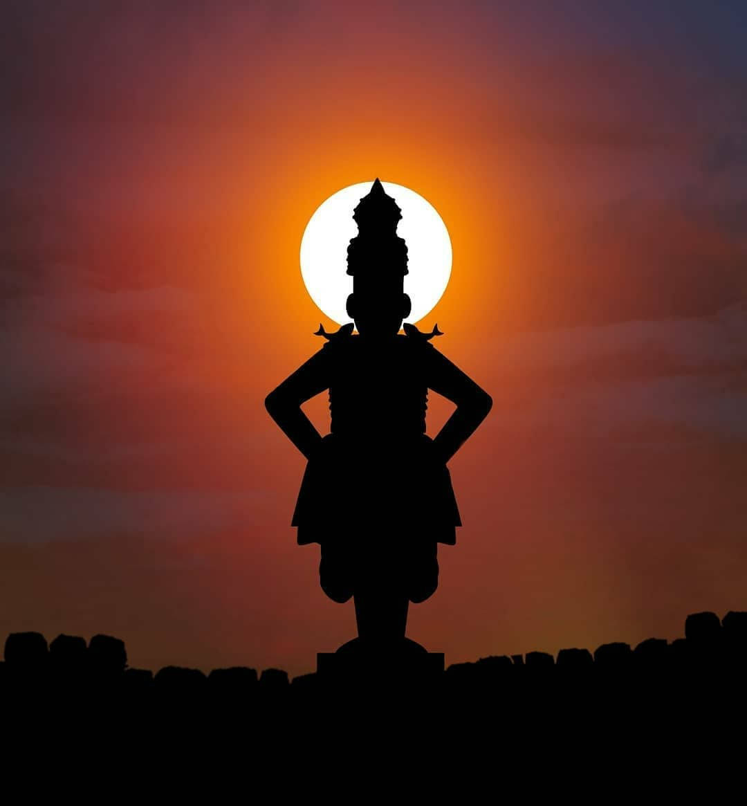 Indian 桌布 壁紙 — 戴冠神像的剪影自信地矗立在發光的橙色日落天空前。
