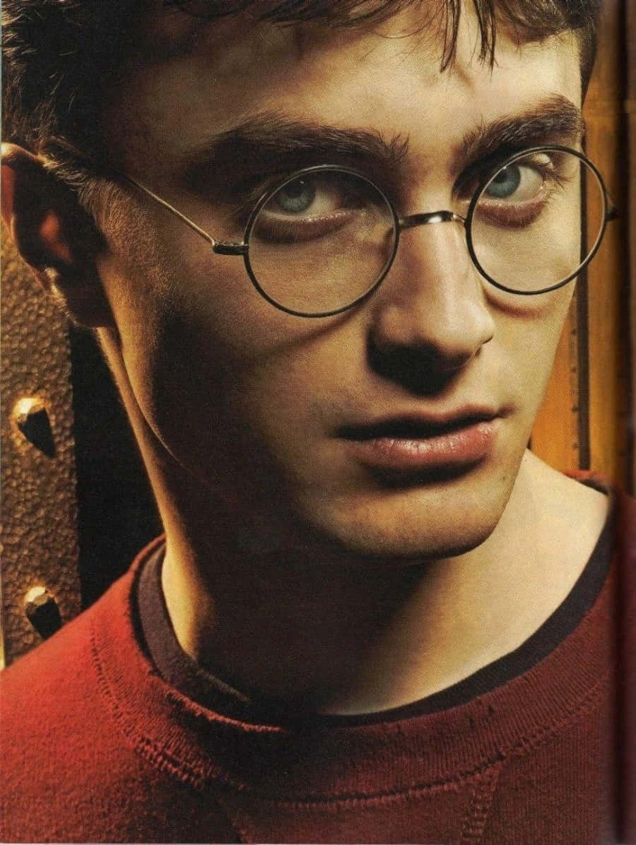 Harry Potter Profile 桌布 壁紙 — 戴圓框眼鏡、穿紅色毛衣的年輕男子特寫肖像，眼神專注。