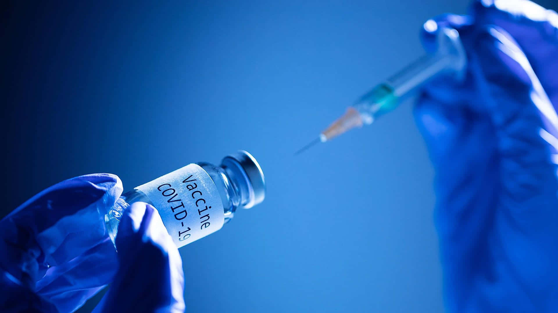 injection 桌布 壁紙 — 戴手套的手在清涼的藍色背景下拿著 COVID-19 疫苗瓶和注射器。