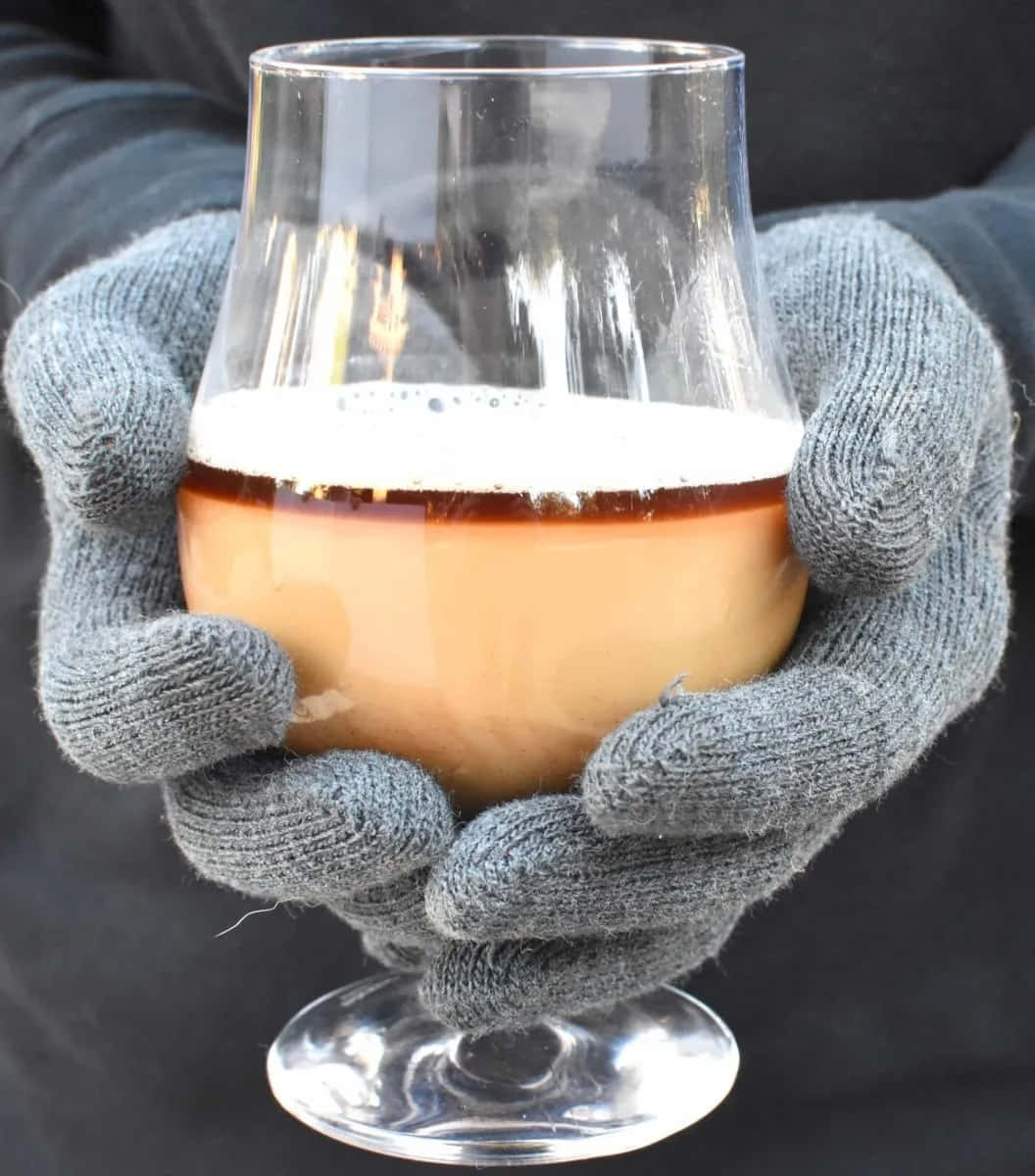 Winter Drinks 桌布 壁紙 — 戴手套的手在黑暗背景前捧著一杯泡沫啤酒。