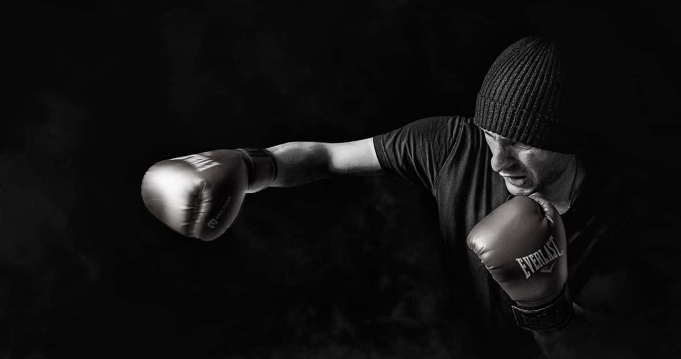 Boxing 桌布 壁紙 — 戴毛帽的拳擊手在煙霧繚繞的戲劇性黑白畫面中揮出一拳。