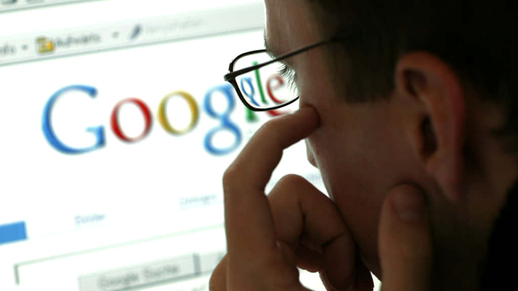 戴眼鏡的人看著電腦上的Google搜尋頁面思考。 — Google Meet 壁紙