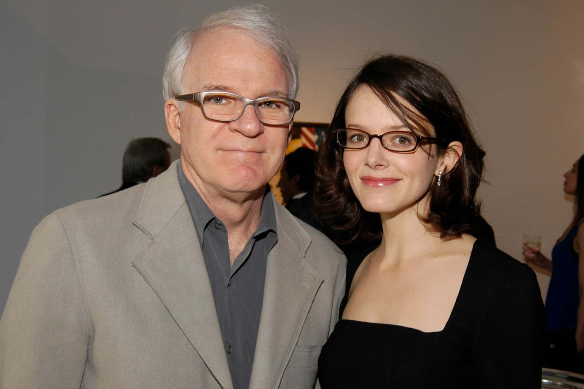 steve martin 桌布 壁紙 — 戴眼鏡的男人和女人在室內柔和燈光下的社交聚會中一起微笑。
