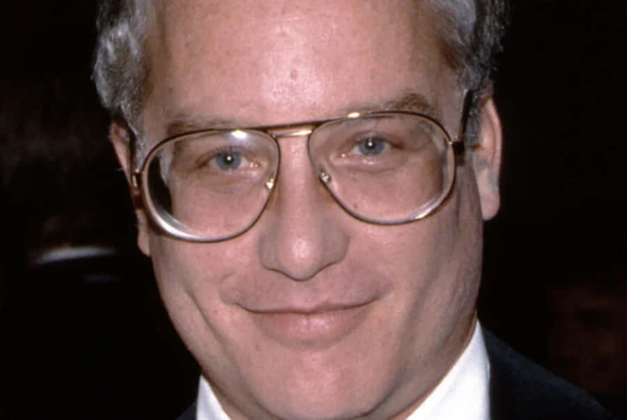 Richard Dreyfuss 桌布 壁紙 — 戴粗框眼鏡、灰白頭髮、身穿西裝白襯衫的微笑男士特寫肖像。