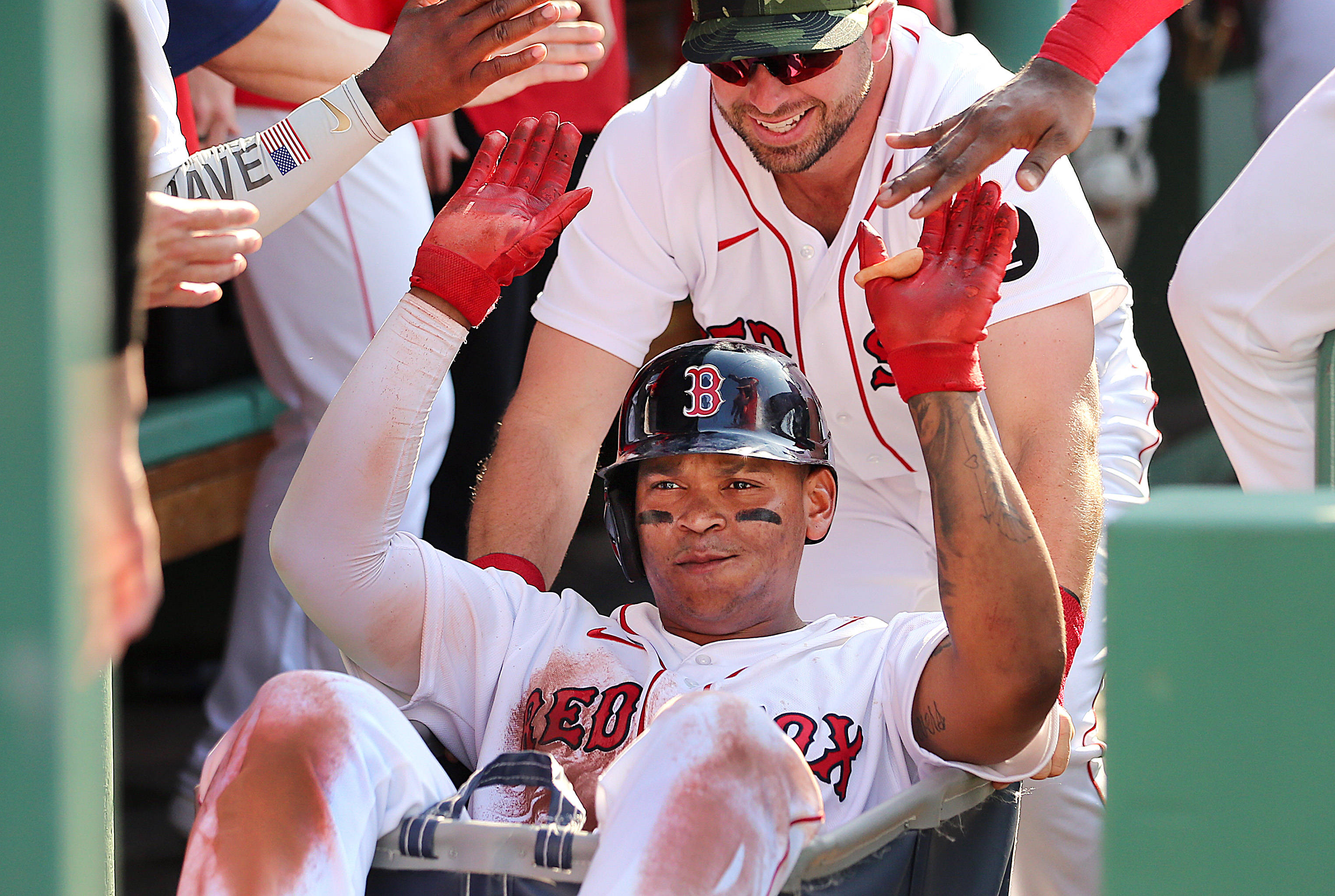Red Sox 桌布 壁紙 — 戴紅色頭盔、身穿白色球衣的棒球手在陽光明媚的比賽中與休息區的隊友擊掌。